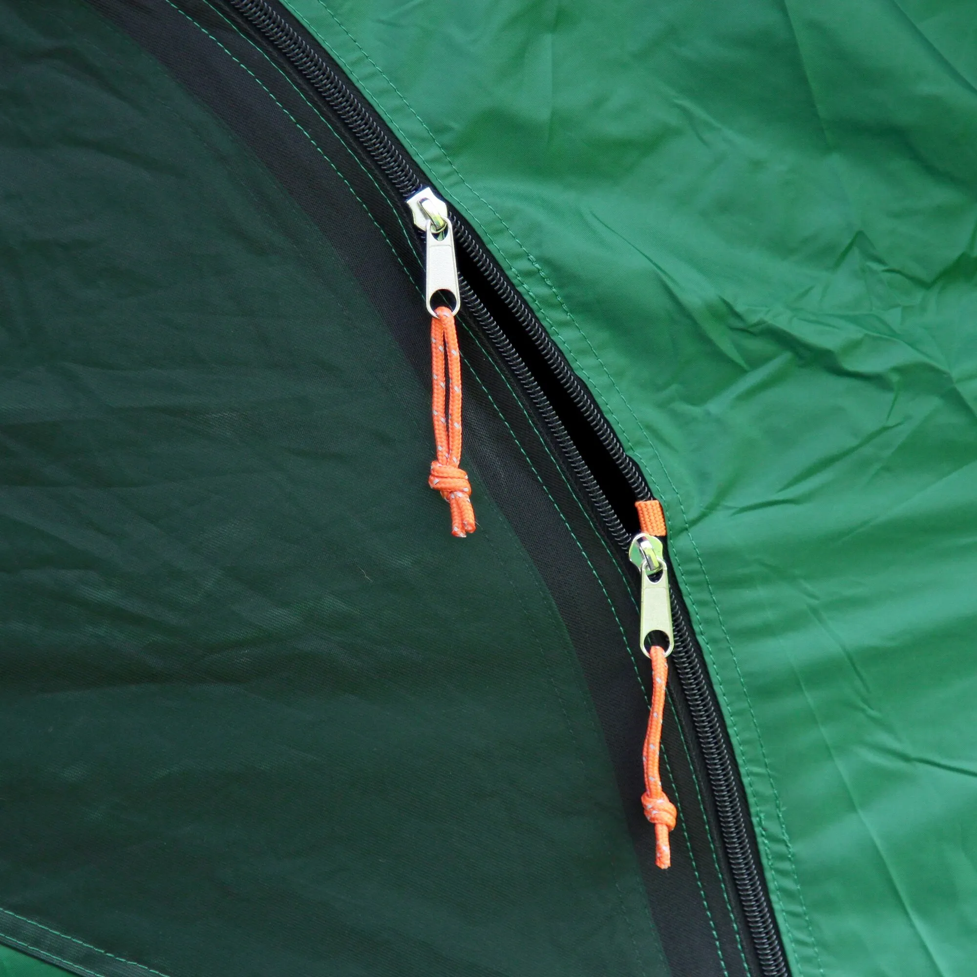 Detailaufnahme des grünen Tunnelzelts Chimney Rock 3 Plus Blackout mit schwarzen Reißverschlüssen und orangefarbenen Kordelgriffen