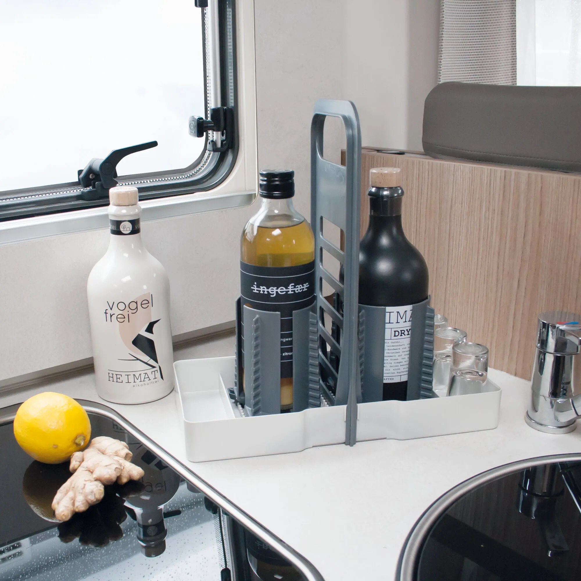 Hellgrauer Flaschenhalter Multi Tray OELE mit drei Flaschen und Gläsern auf der Küchenarbeitsplatte in einem Wohnmobil