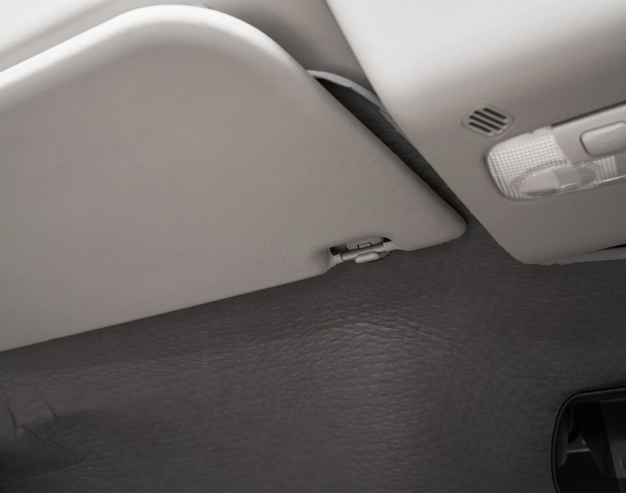 Anthrazitfarbene Innenisoliermatte Travel im Dachbereich eines Ford Transit, neben Sonnenblende und Innenleuchte