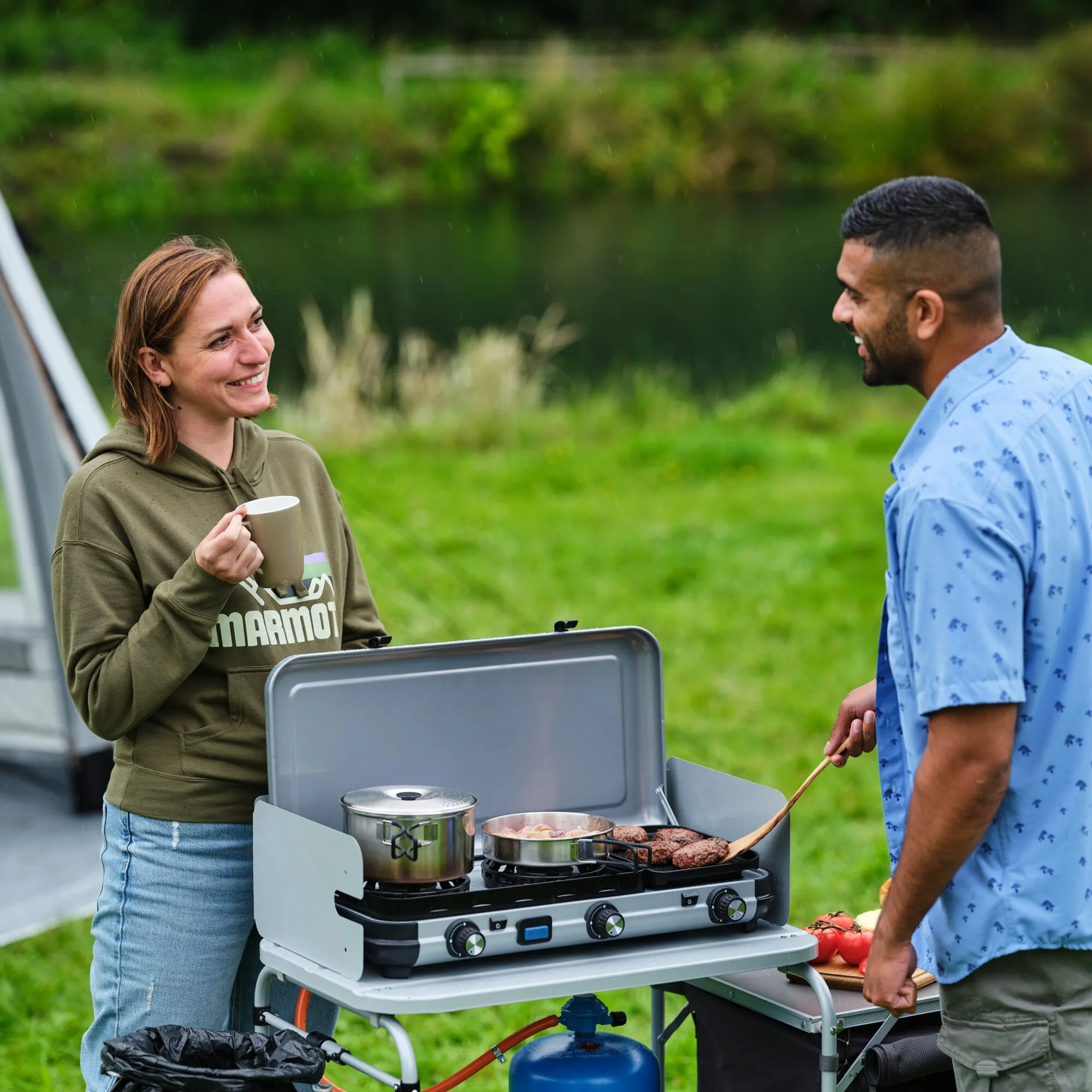 Zwei Personen kochen im Freien am Gaskocher Camping Kitchen 2 MULTI-COOK mit Topf, Pfanne und Grillplatte am Gasflaschenanschluss