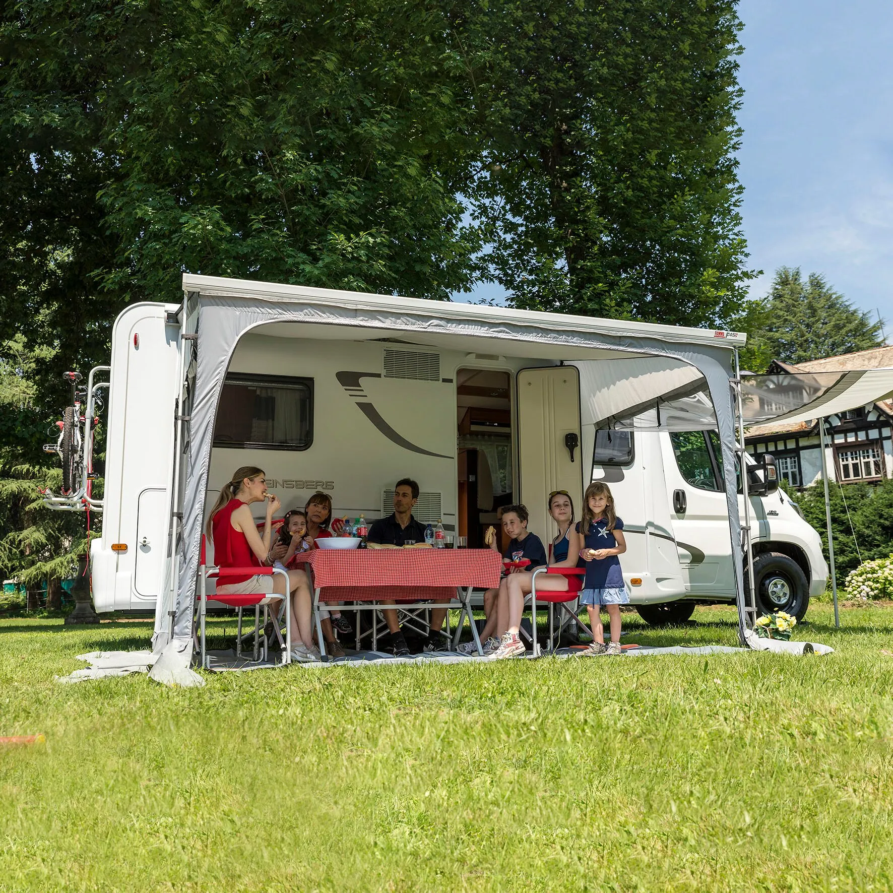 Graues Markisenzelt Privacy Ultra Light, 450 cm, an einem weißen Wohnmobil mit Familie beim gemeinsamen Essen im Freien