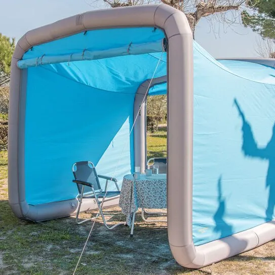 Blaue Frontwand der Camping GT Box mit aufblasbarem grauem Rahmen, Campingstühlen und gedecktem Tisch im Innenraum
