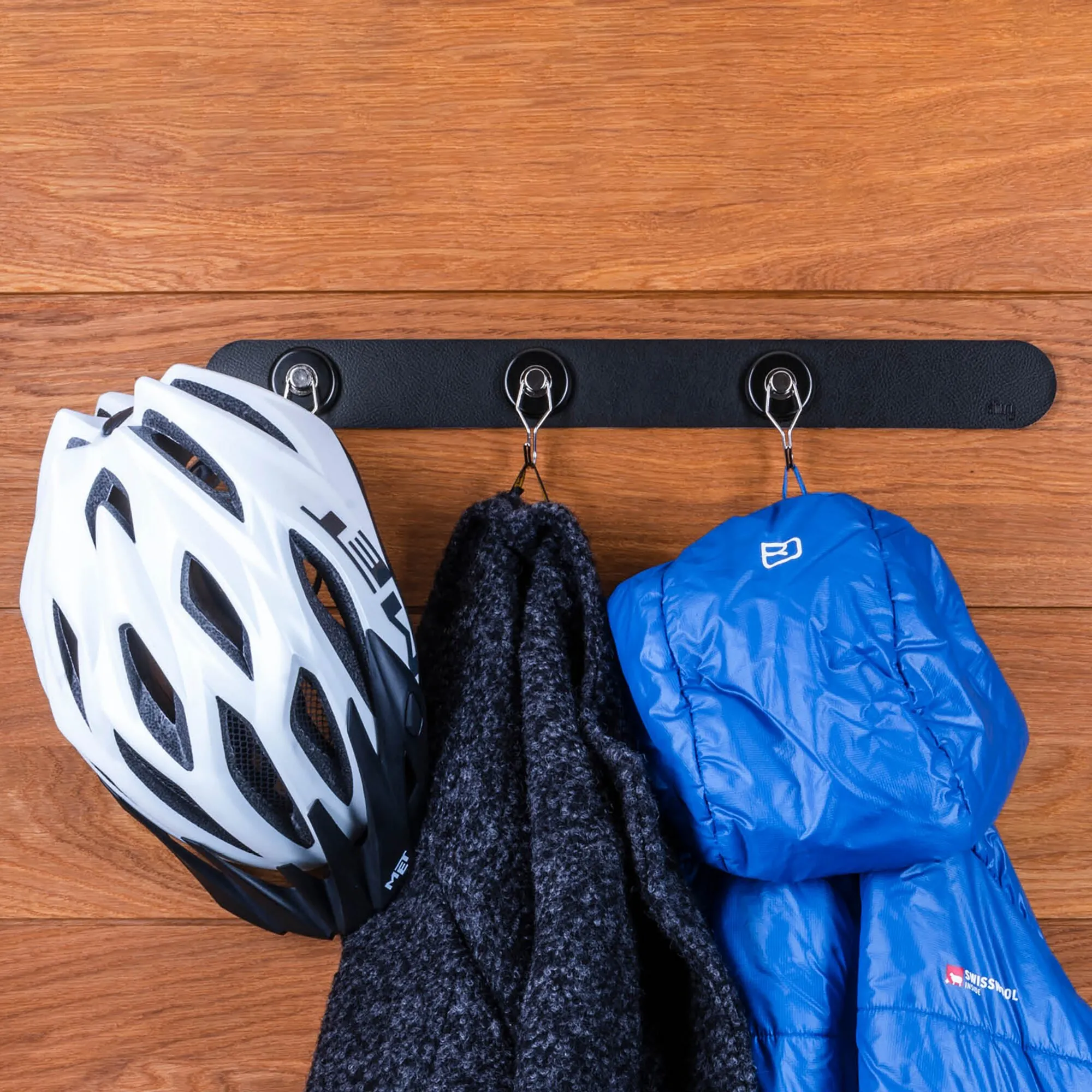Schwarze 500-mm-Metallleiste mit drei Haken, an denen Fahrradhelm, Schal und blaue Jacke hängen