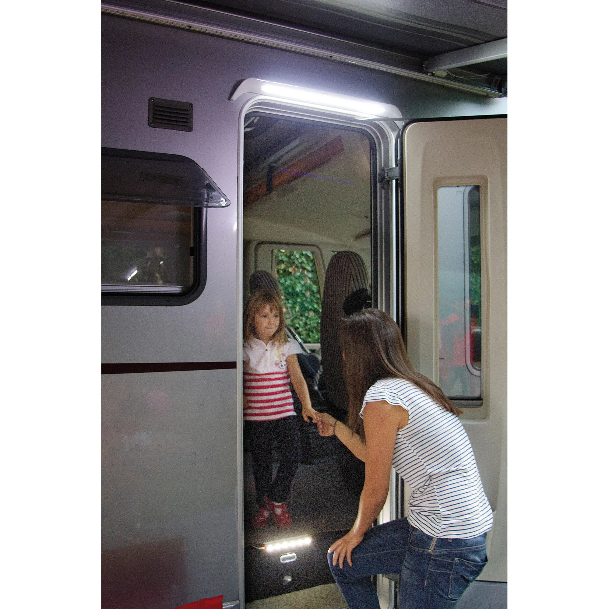 Wohnmobilseitige Türöffnung mit einer hellen LED-Leiste in einer Rinne über der Tür, im Innenraum sind zwei Kinder sichtbar