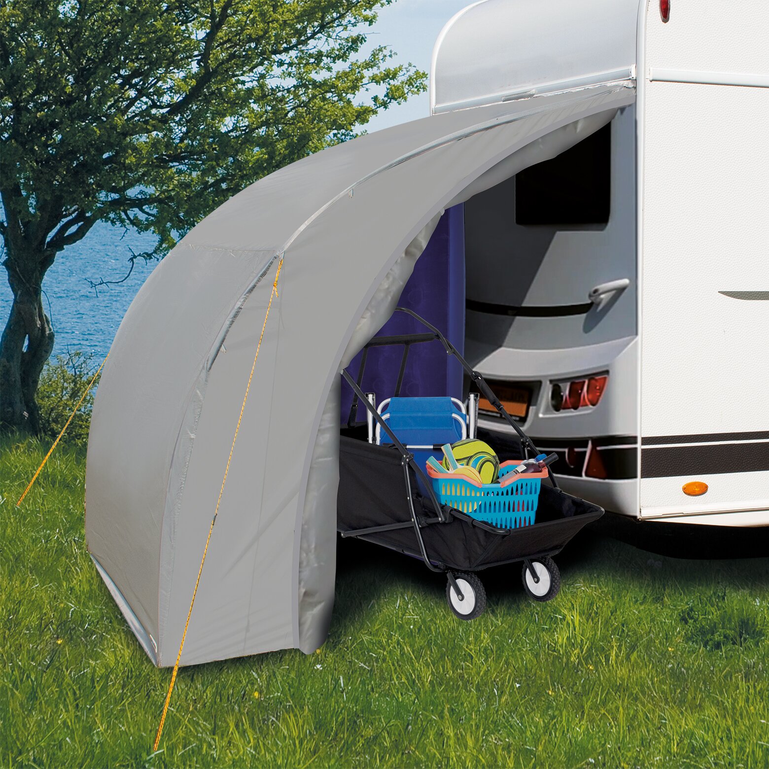 Seitenansicht einer Heckgarage Deluxe am Wohnmobil; davor ein Klappwagen mit Spielzeugkorb, Gras, See und Bäume im Hintergrund