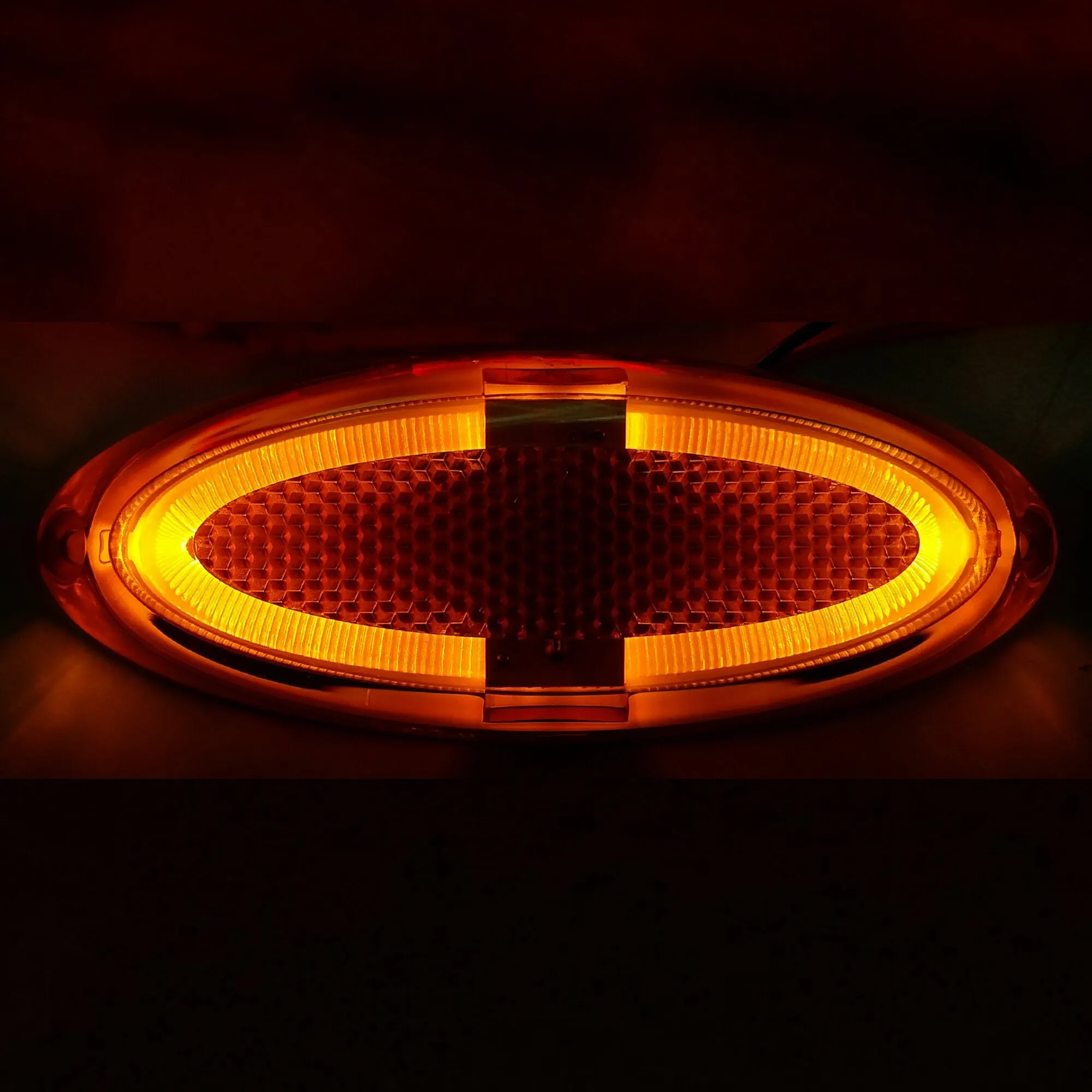 Oval geformte orange Markierungsleuchte in Nahaufnahme mit leuchtendem Wabenreflektor und geripptem Lichtkranz