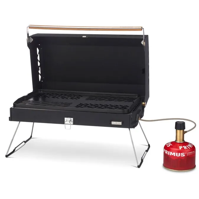 Schwarzer Gasgrill Kuchoma mit geöffnetem Deckel, klappbaren Standbeinen und angeschlossener roter Primus-Gaskartusche