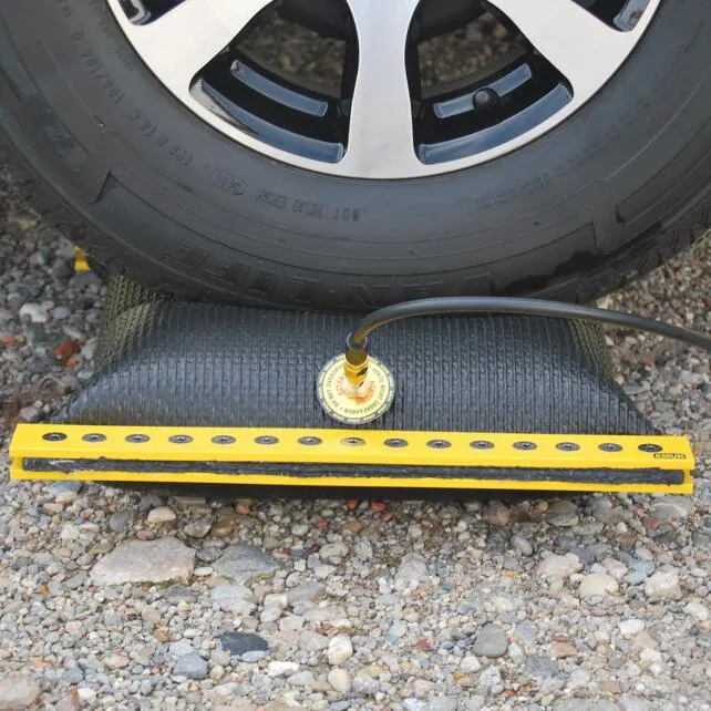 EMUK Air-Lift® 2 Ausgleichskissen mit gelber Auffahrschiene unter einem Fahrzeugreifen auf Schotter grasalt?