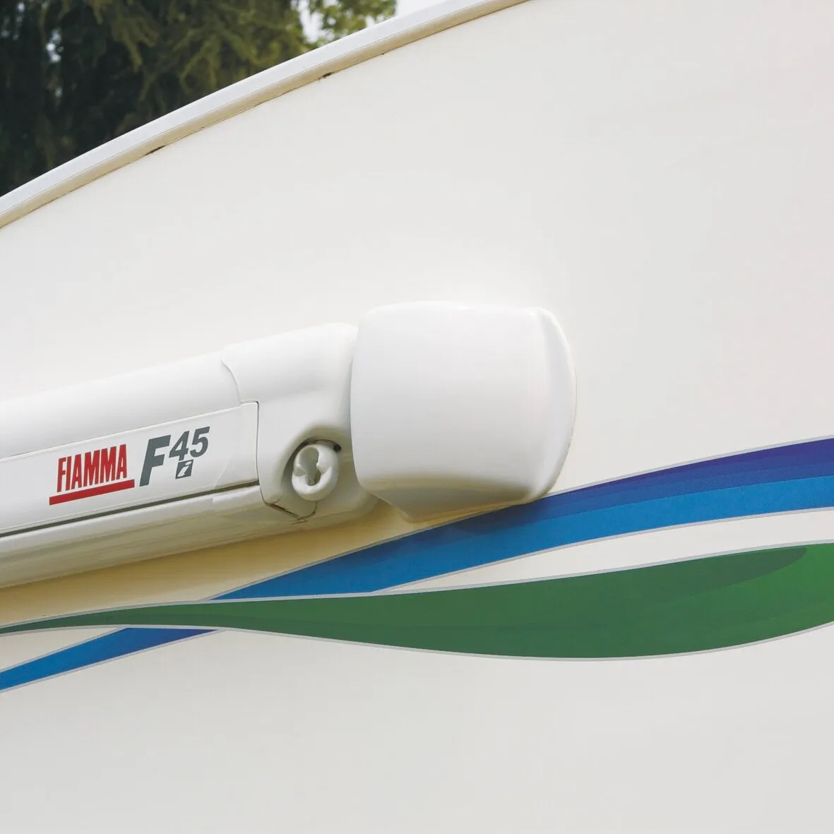 Detailaufnahme eines polarweißen Markisenspoilers mit FIAMMA F45-Markise und blau-grün gestreiftem Markisentuch
