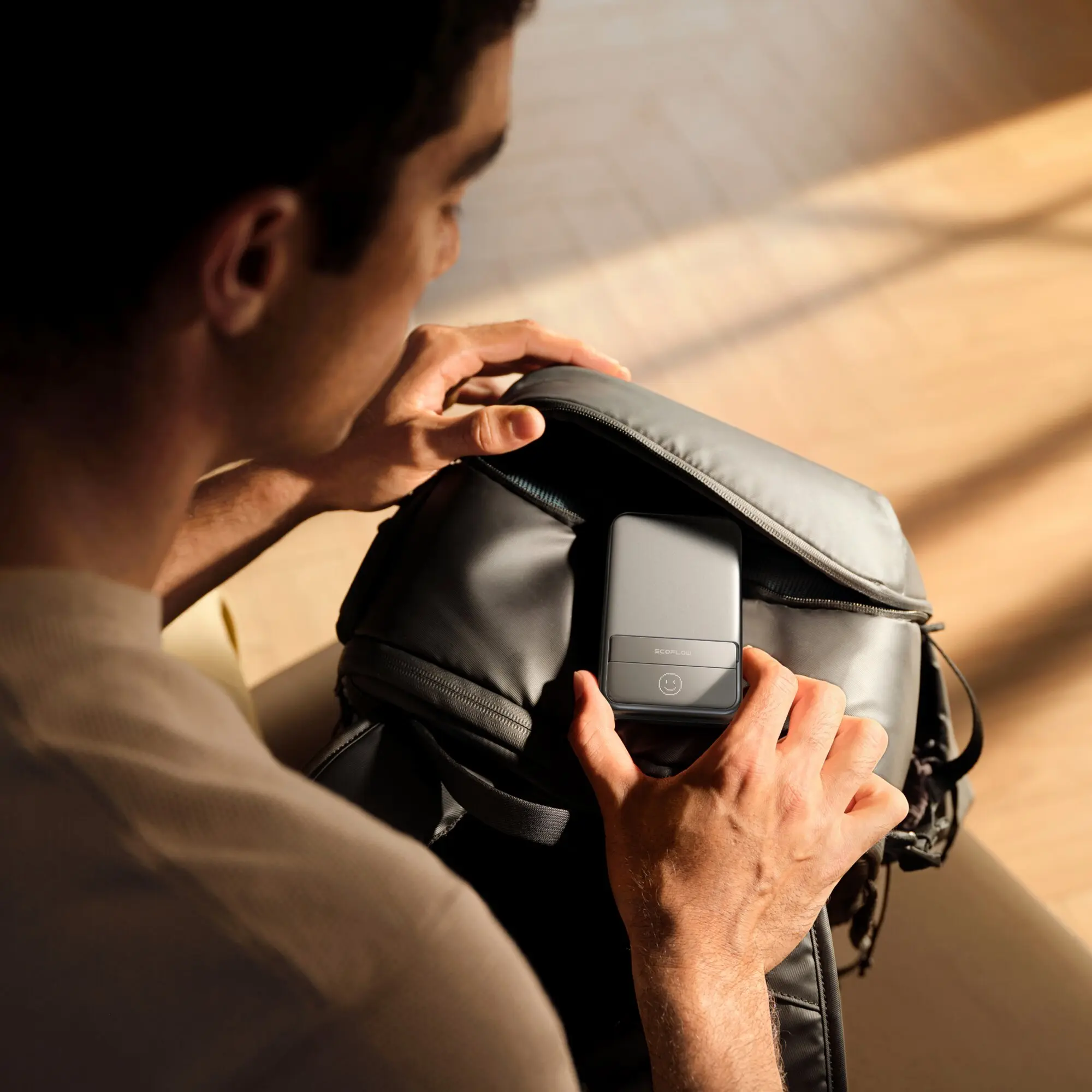 Person im Profil mit Rucksack zeigt magnetische Powerbank Rapid 5000 mAh am Schulterriemen befestigt, graues flaches Gehäuse mit EcoFlow-Logo