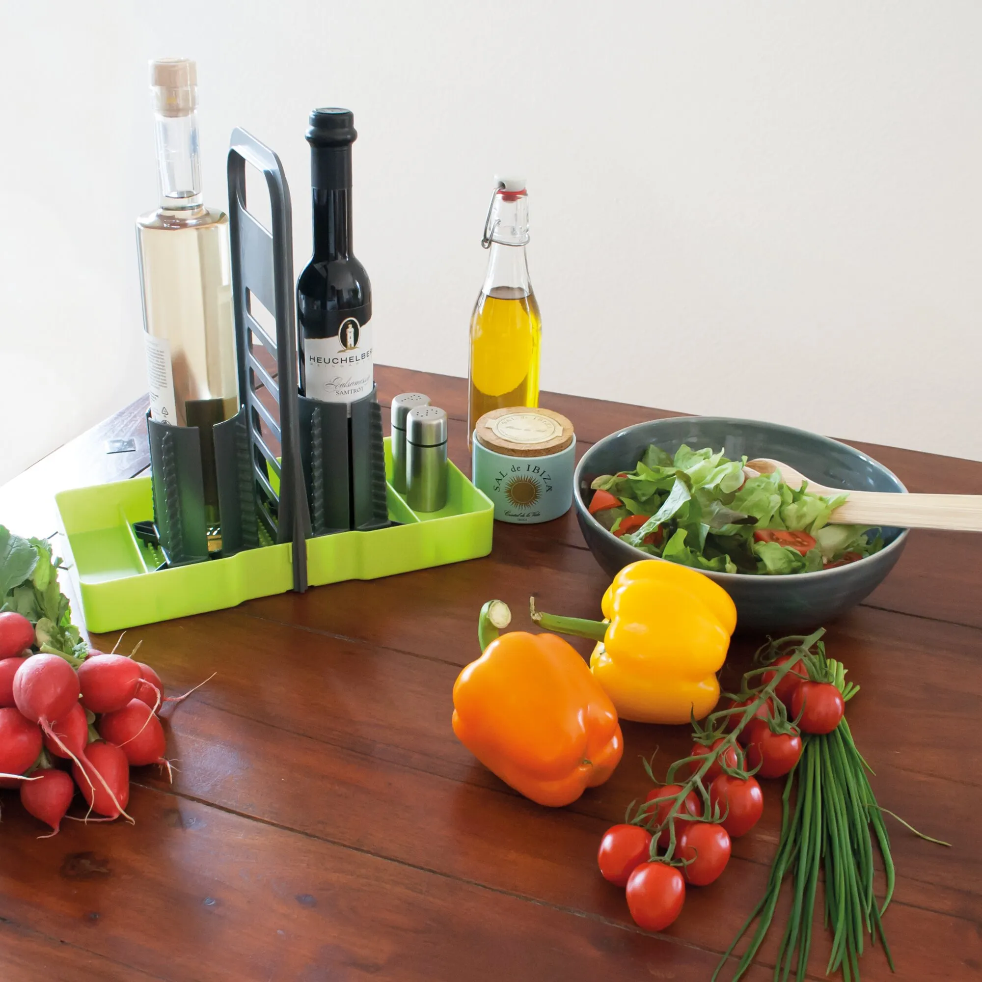 Limegrüner Flaschenhalter Multi Tray OELE mit mehreren Flaschen und Gewürzstreuern auf einem Esstisch neben Salat und Gemüse