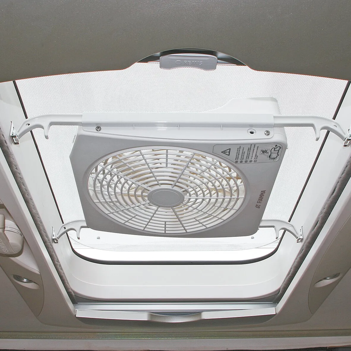 Dachhaubenventilator Turbo Kit mit weißem Schutzgitter, montiert an der geöffneten Dachluke eines Wohnmobils
