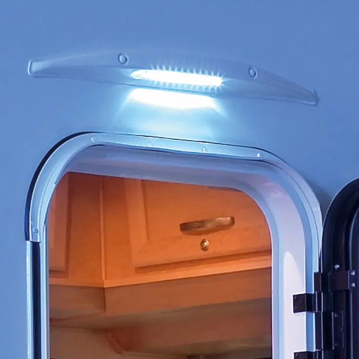 Außenansicht eines Caravan-Portal mit einer flachen LED-Vorzeltleuchte in transparentem Gehäuse, die helles Licht nach unten wirft