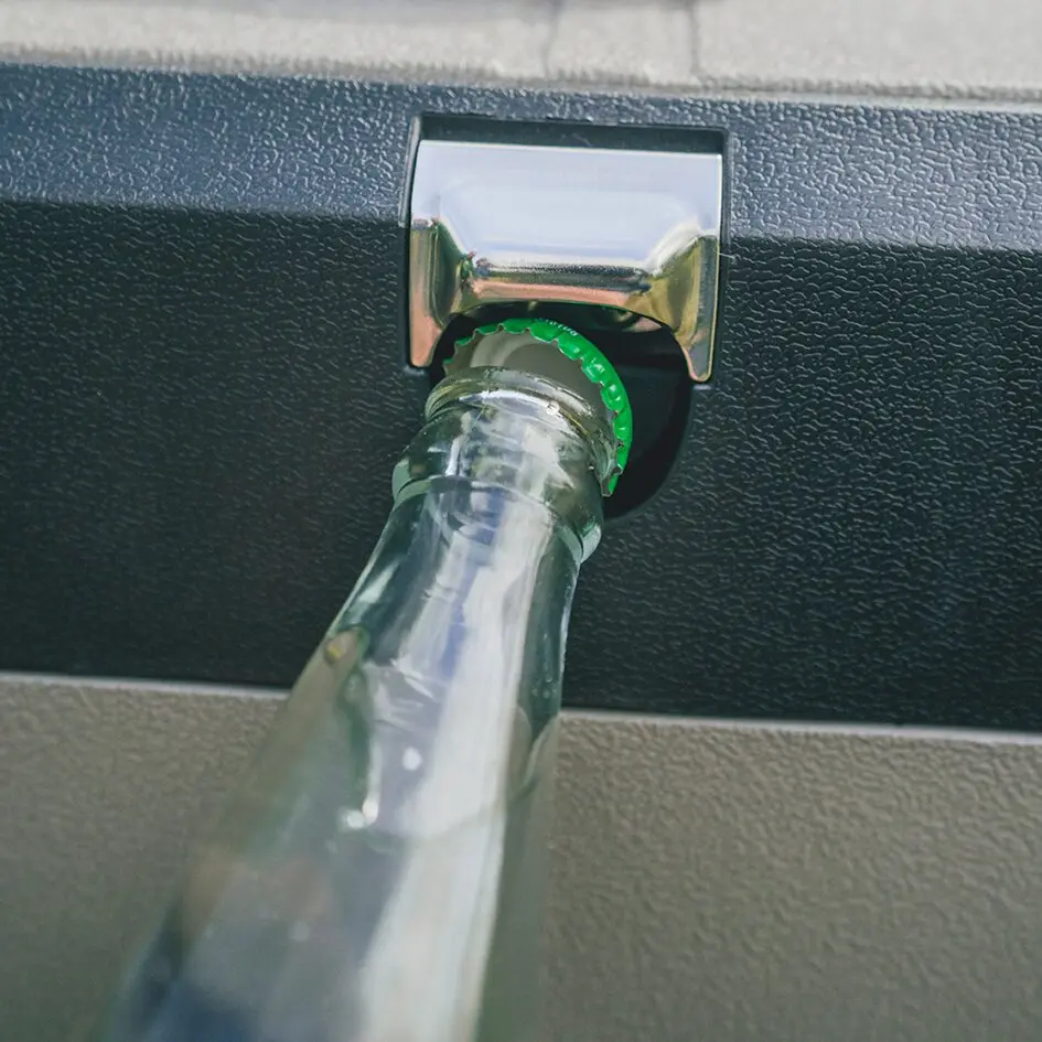 Nahaufnahme einer Glasflasche mit grünem Flaschenhals, die in eine dunkle Kühlbox eingesetzt wird
