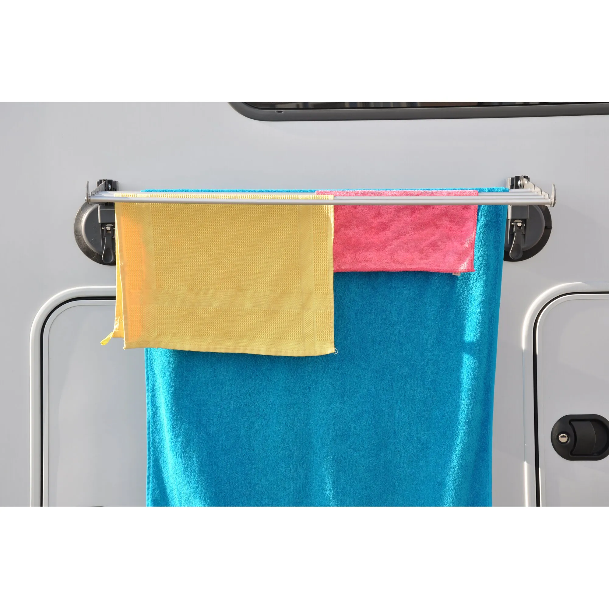 Wäschetrockner mit aufgehängten gelben, pinken und blauen Handtüchern an einer Trockenvorrichtung