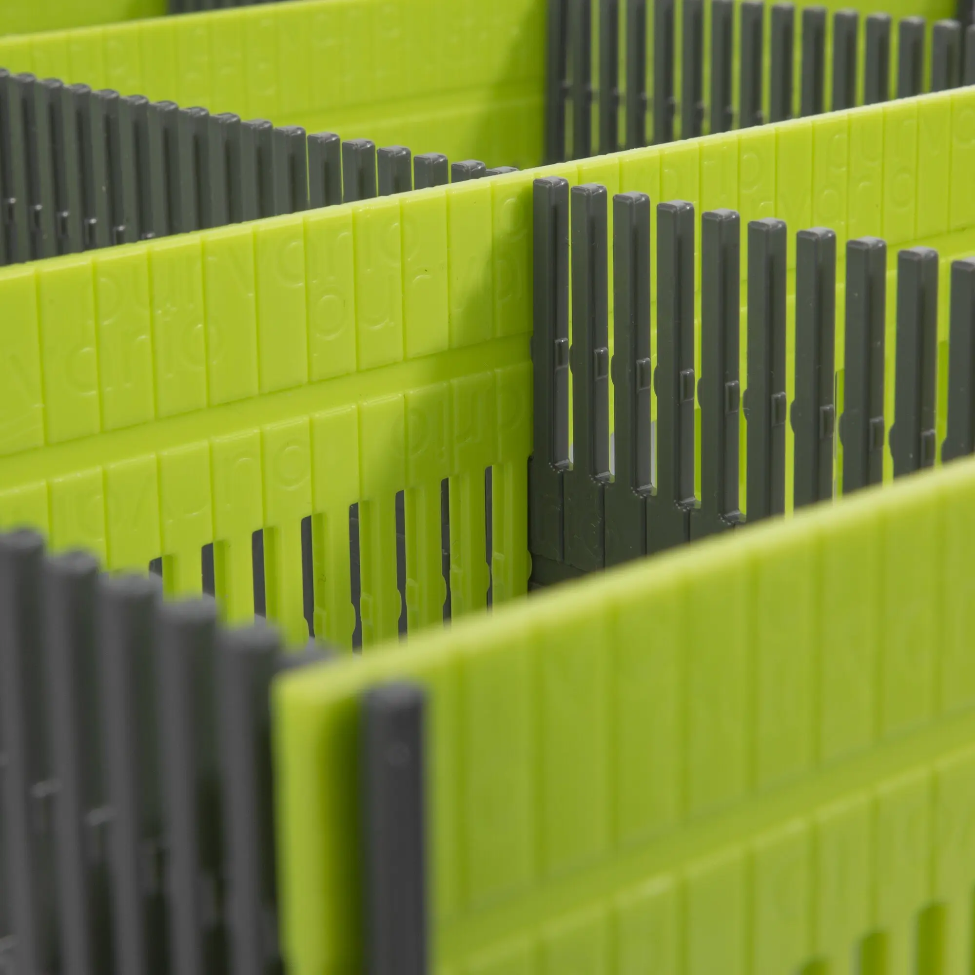 Detailaufnahme einer limegrünen Stauleiste für Schubladen mit grauen senkrechten Stäben in einem modularen Aufbau