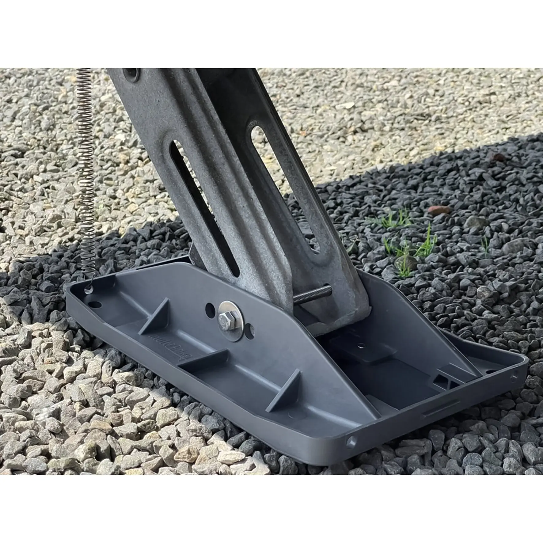 Abstützfuß mit Stützplatten aus Stahl, Schlitze in der Stützplatte und seitlich sichtbare Feder, liegt auf Kies