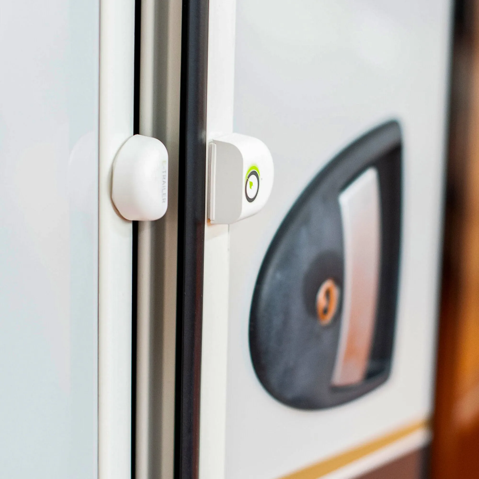 Weißer E-Switch-Sensor zur Tür- und Fensterüberwachung, zweiteilig an einem Fensterrahmen montiert, Detailaufnahme