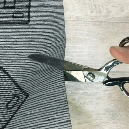 Detailaufnahme des grau-schwarz gestreiften Läufers Runner Kamper, der mit einer Schere zugeschnitten wird