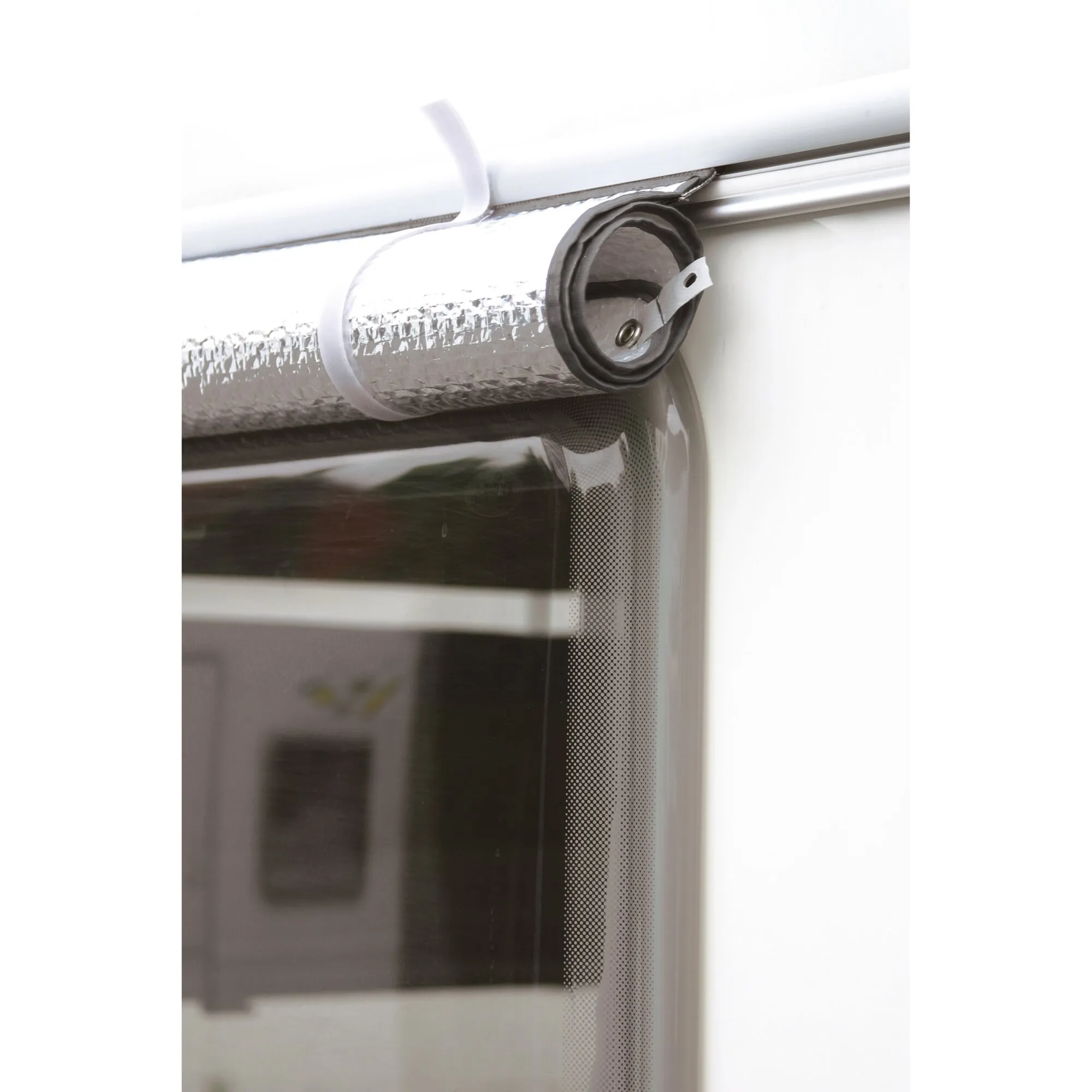 Silberne Thermomatte aus Luftpolsterfolie, aufgerollt und mit Druckknopfband an einem Wohnwagenfenster befestigt