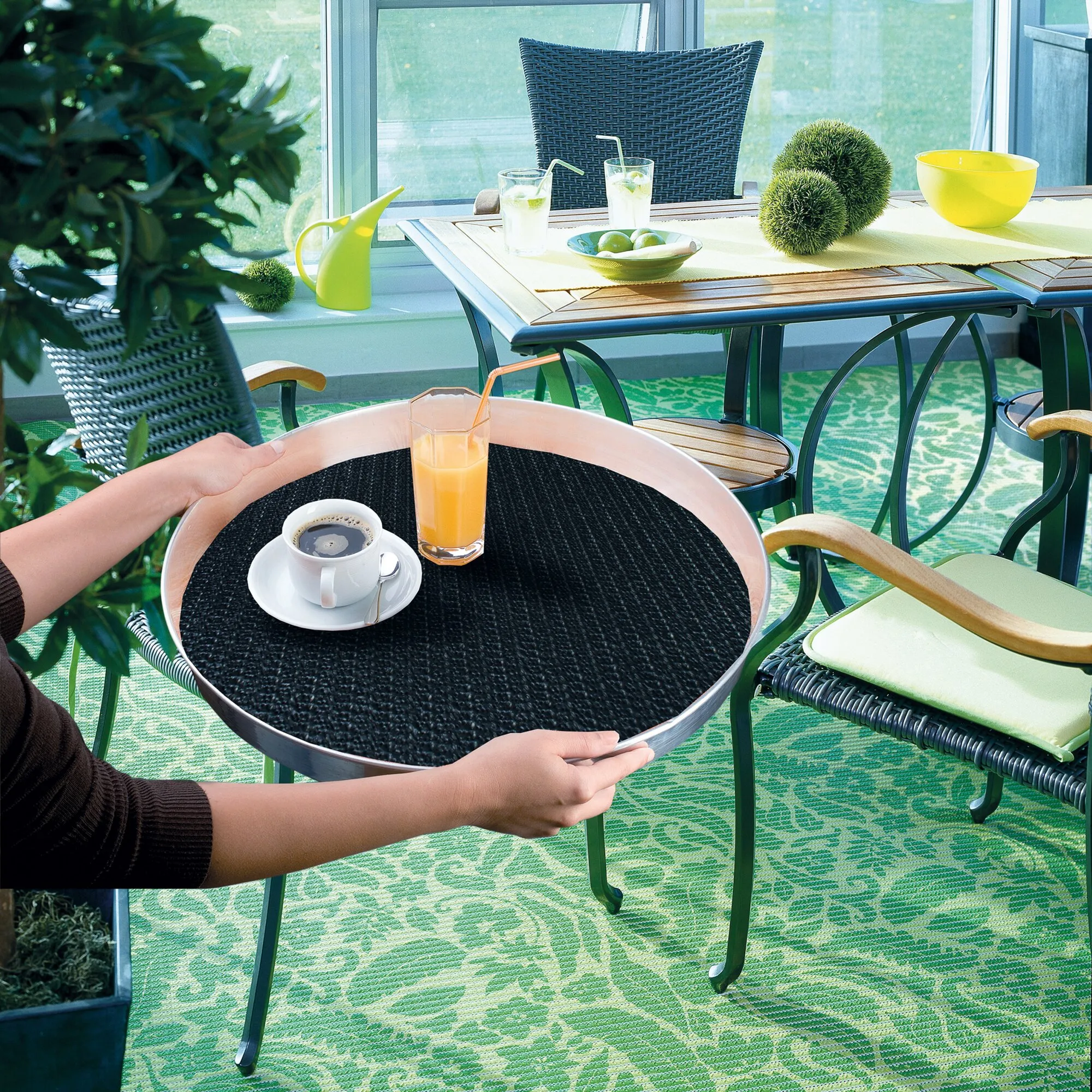 Schwarze runde Antirutschmatte mega-stop in einem Serviertablett mit Kaffee und Saft auf einer Terrasse