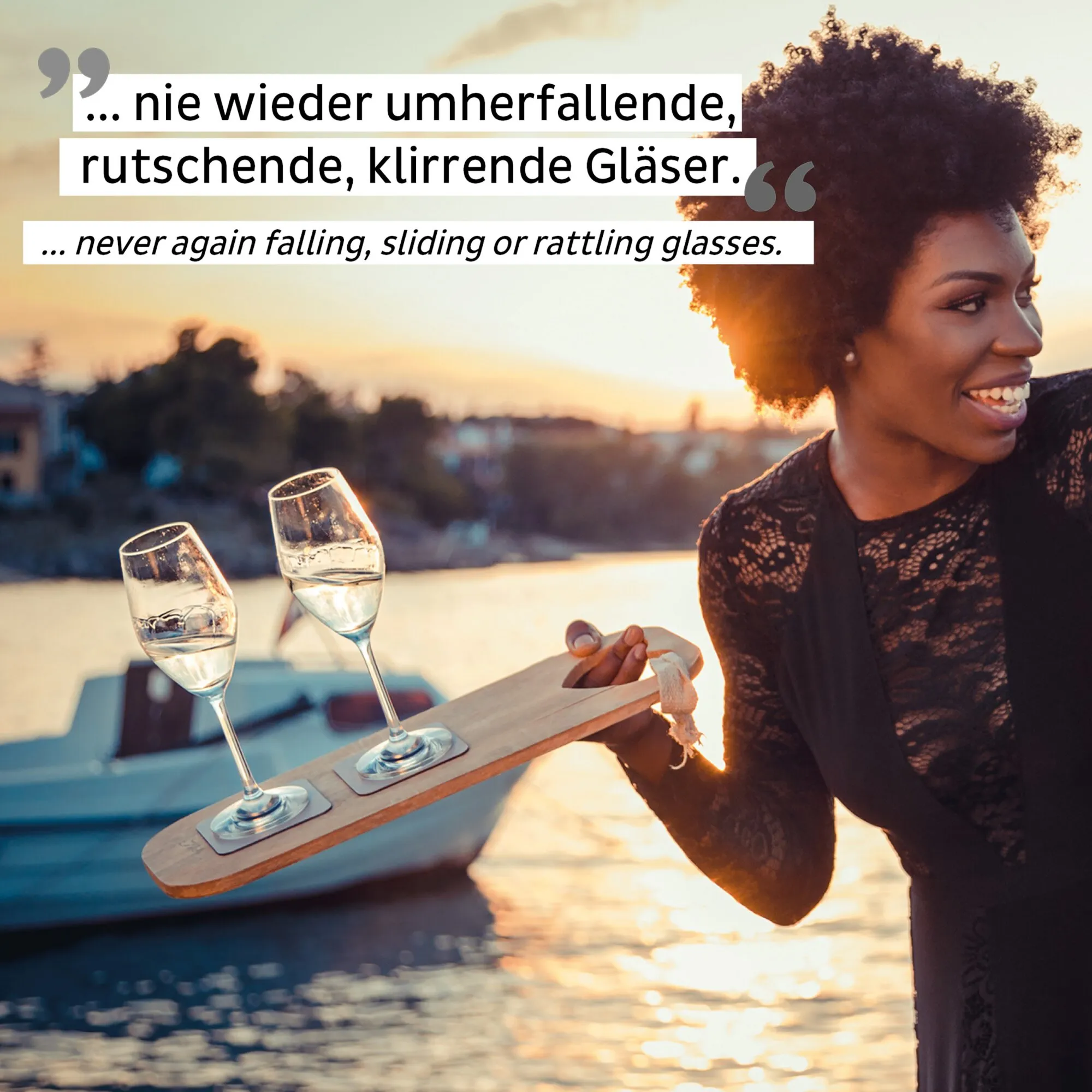 Frau hält bei Sonnenuntergang ein Holzbrett mit zwei gefüllten Magnet-Kristallgläsern für Champagner mit quadratischen Magnetfüßen in der Hand