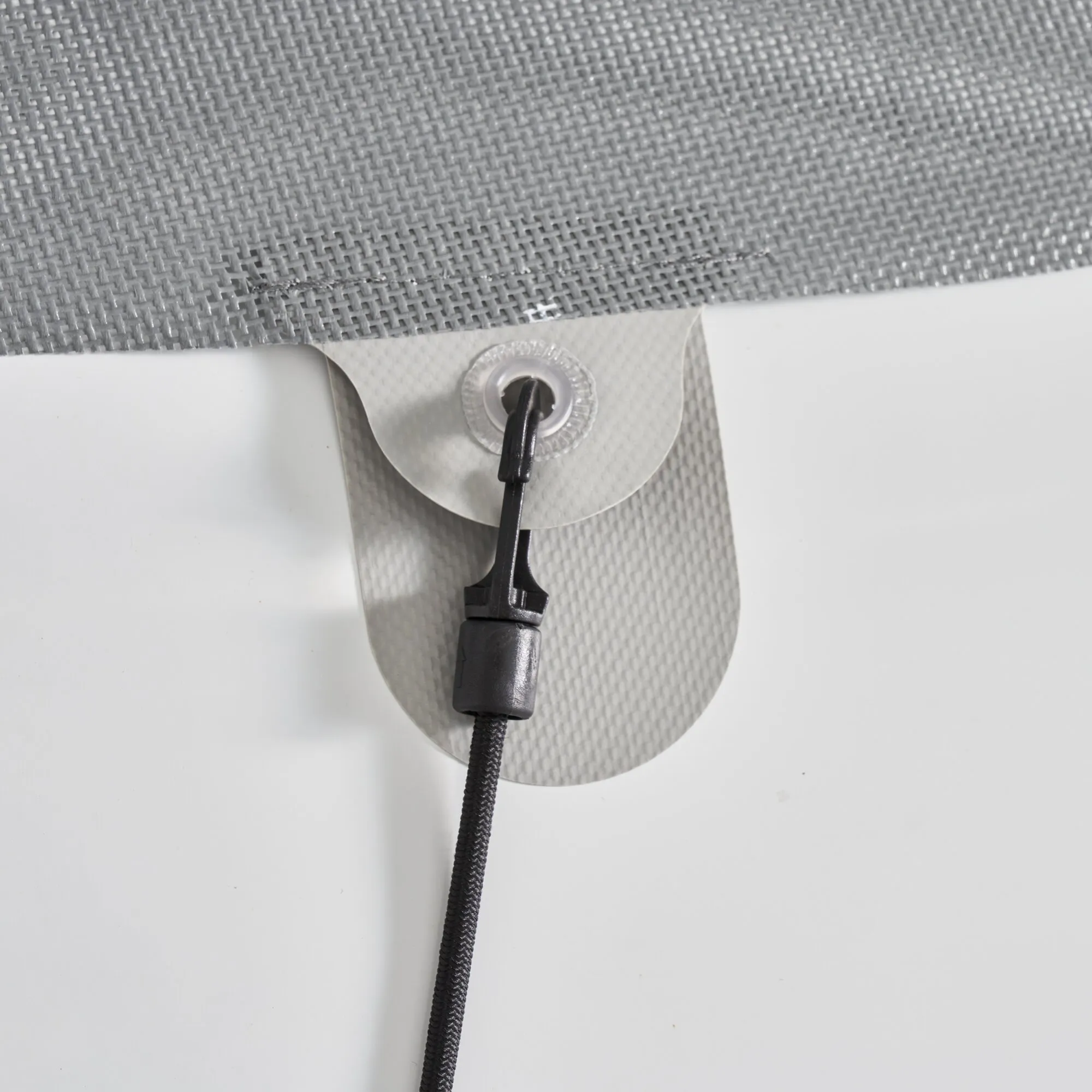 Detailaufnahme der grauen Sonnenschutzmatte Screen mit verstärkter Öse und schwarzer Befestigungsschnur samt Kunststoffhaken