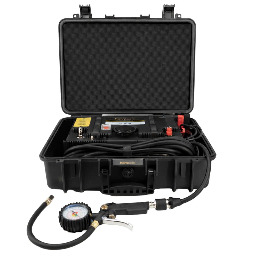 Geöffnetes schwarzes Hartschalenkoffer mit Schaumstoffeinlage und tragbares Kompressor-Kit, inklusive Manometer, Schlauch und Reifen-Inflator