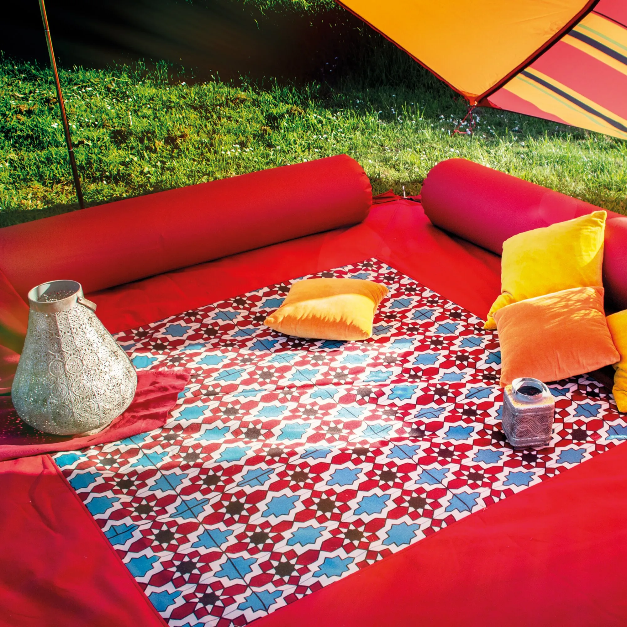Roter Teppich Zip Carpet mit blau-weißem und rotem geometrischem Muster in einer roten Sitzecke im Zelt mit Kissen und Laternen