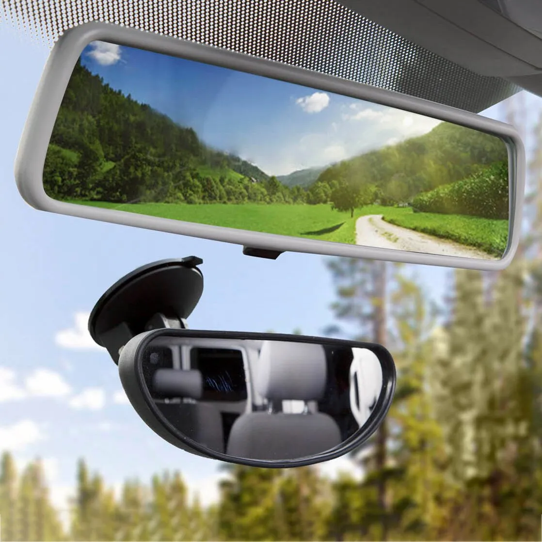 Rückspiegel Retral im Auto mit hellem rechteckigen Rahmen; Landschaftsreflex zeigt Wiesen, Wald und Straße, unten kleiner Zusatzspiegel