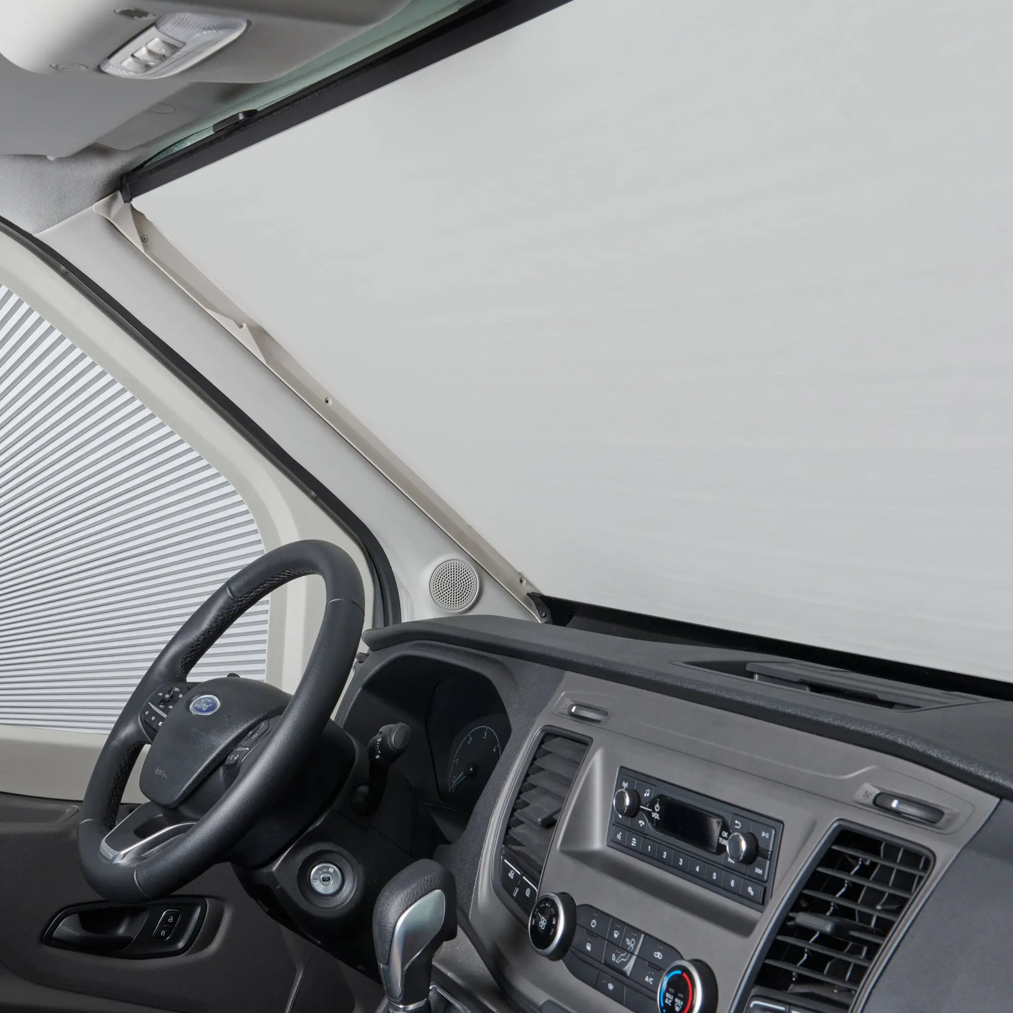 Innenraum eines Ford Transit V363 mit Verdunkelungssystem; grauer Sonnenschutz spannt sich über die Windschutzscheibe, Lenkrad sichtbar