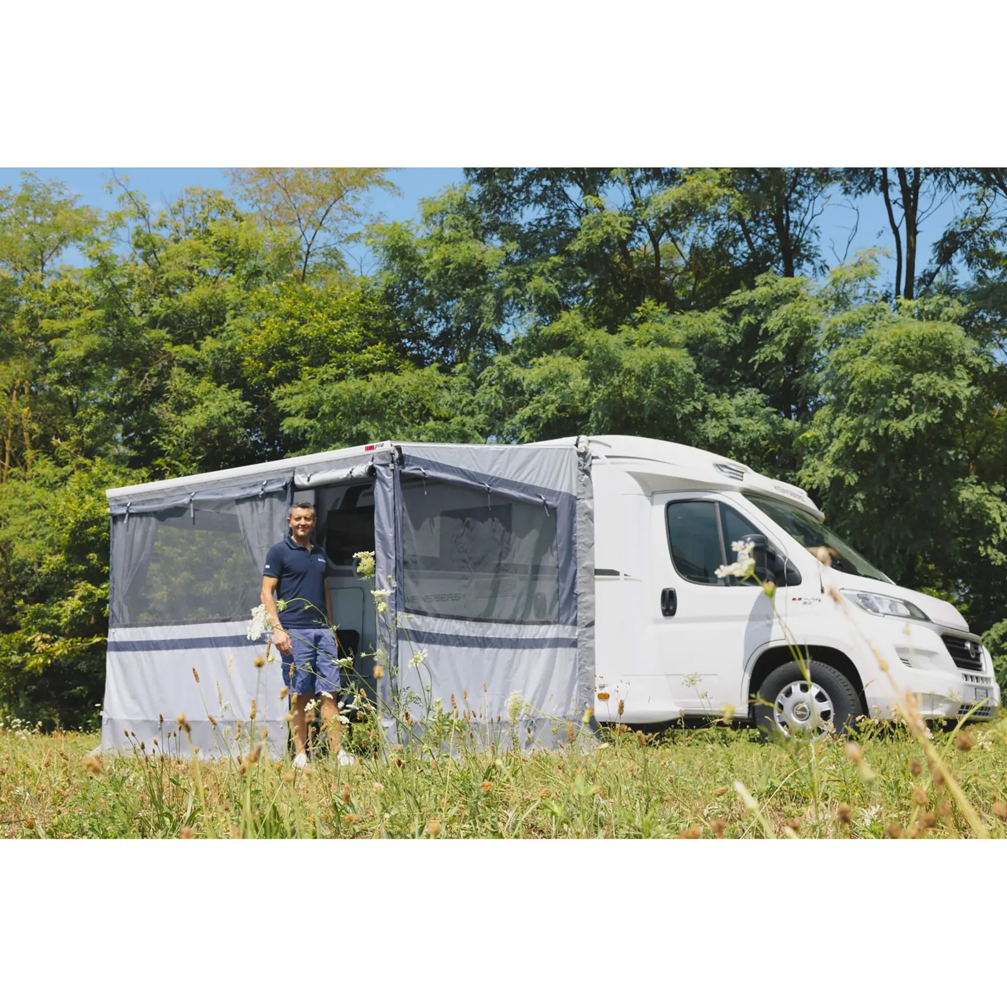 Weißes Wohnmobil mit seitlichem grauen Privacy Room CS Light XL 310 cm, Mesh-Fenstern; eine Person steht davor, Bäume