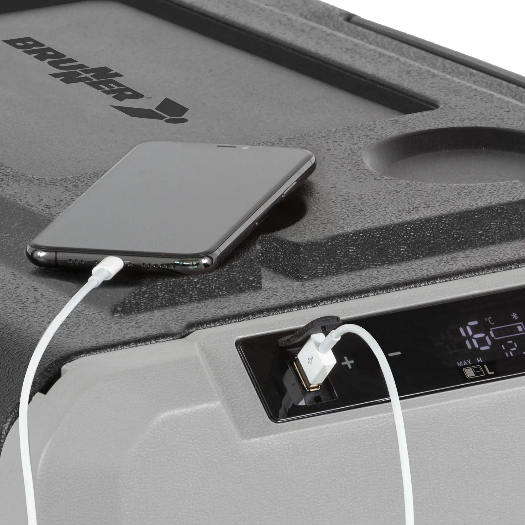 Graue Brunner-Kühlbox im Fahrzeug mit aufgelegtem Smartphone und USB-Kabel; Bedienfeld mit Temperaturanzeige sichtbar