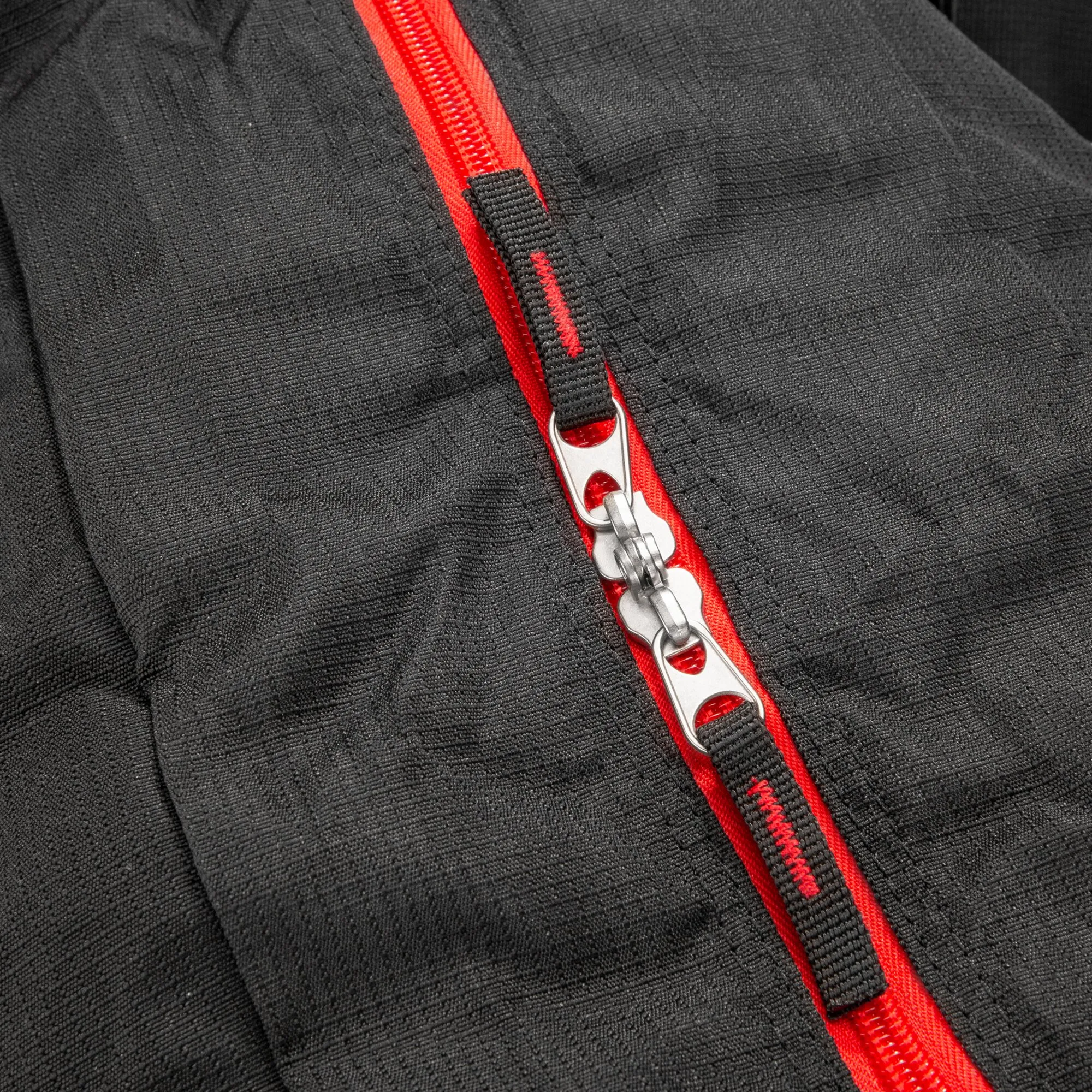 Detailaufnahme der schwarzen Reisetasche Cosmos Duffle 50S mit rotem Reißverschluss und silbernen Doppelschiebern