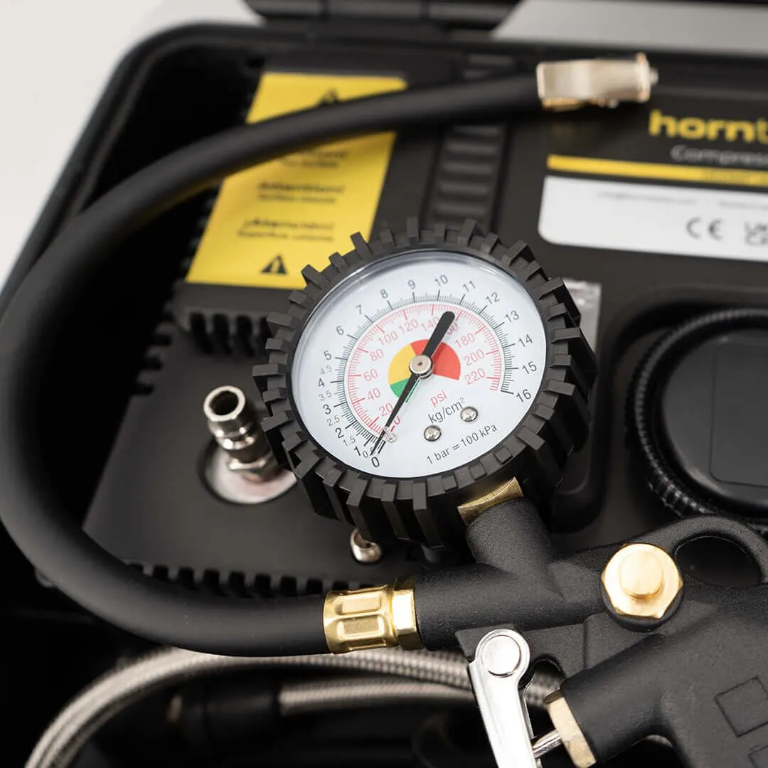 Detailaufnahme einer schwarzen Kompressor-Box mit analogem Druckmanometer, Luftschlauch und Messinganschlüssen