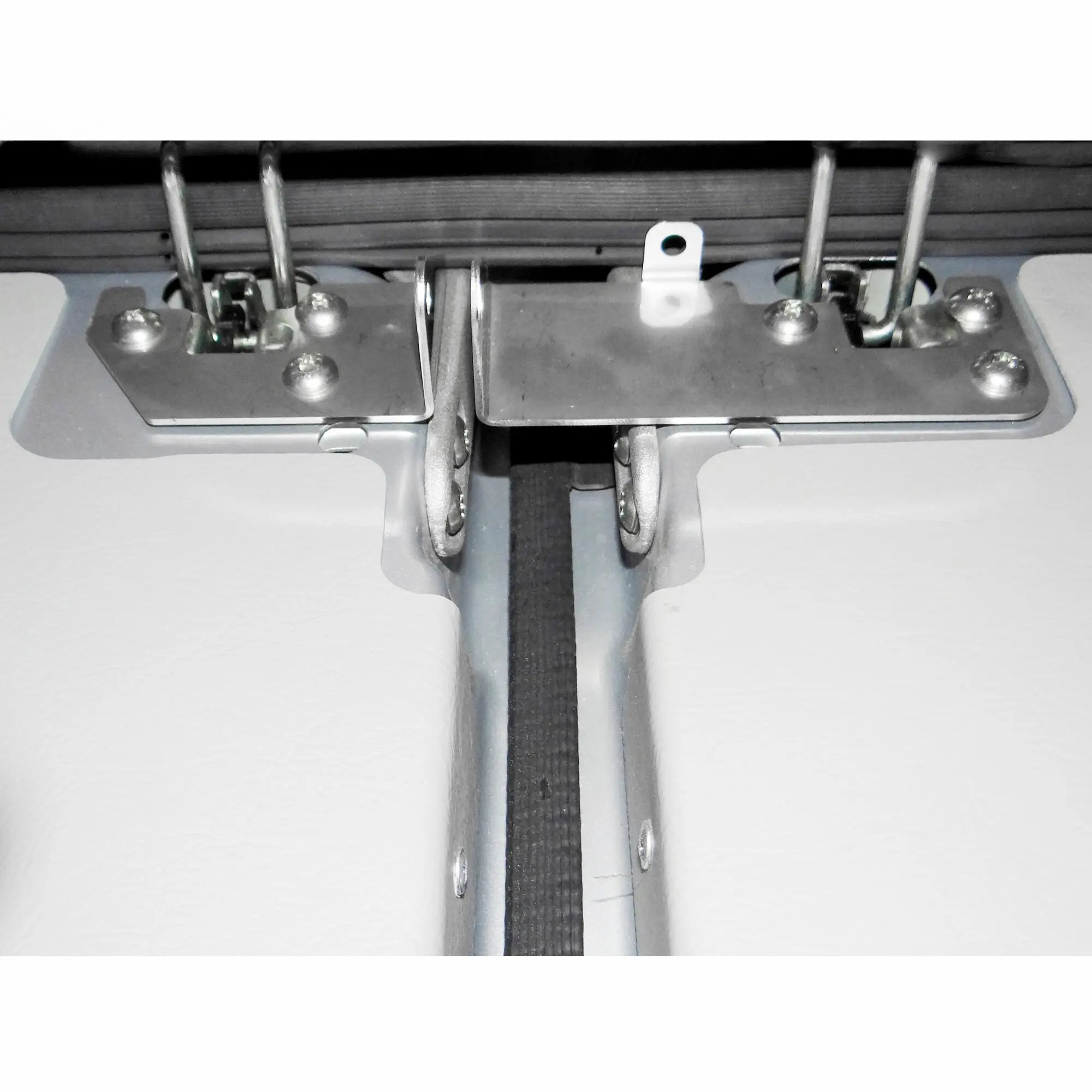 Detailaufnahme eines Türsicherungsmechanismus: Metallbasis mit Schrauben, zwei seitliche Stangen, schwarzes Band in der Mitte und eine weiße Halterung mit Loch