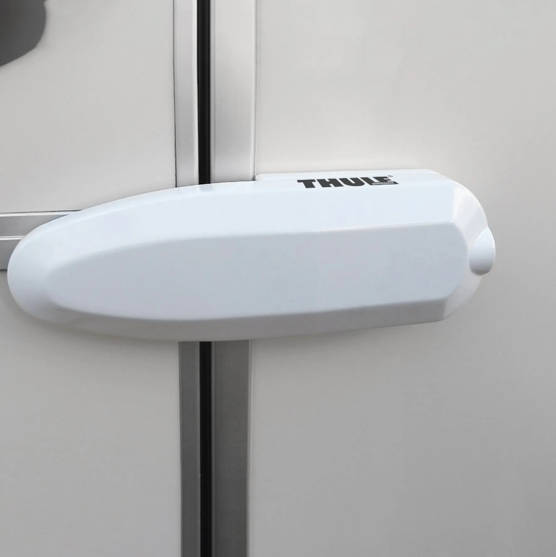 Weißes Thule Universal Lock als Sicherheitsschloss an einer Tür oder einem Fenster montiert