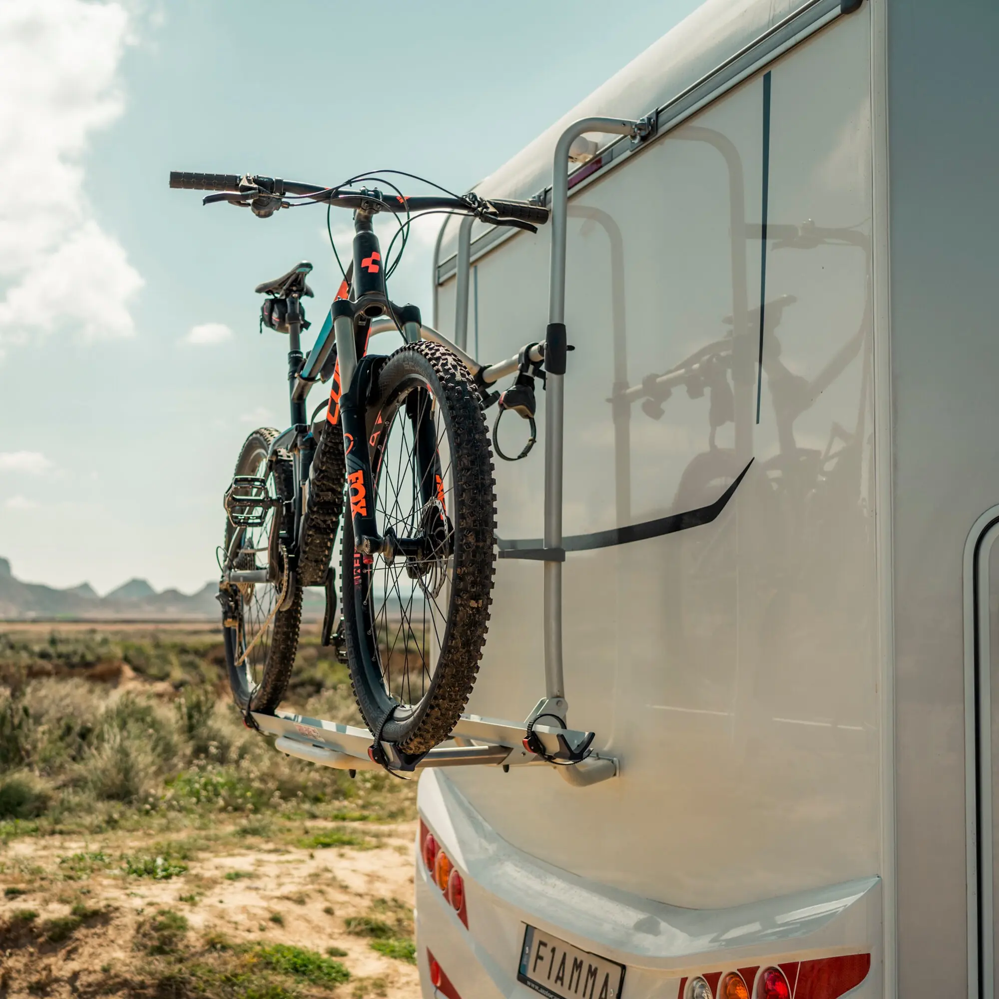 Zwei Mountainbikes am Heck-Fahrradträger eines Wohnmobils, schwarze Rahmen mit orangefarbenen Akzenten, Räder und Lenker sichtbar