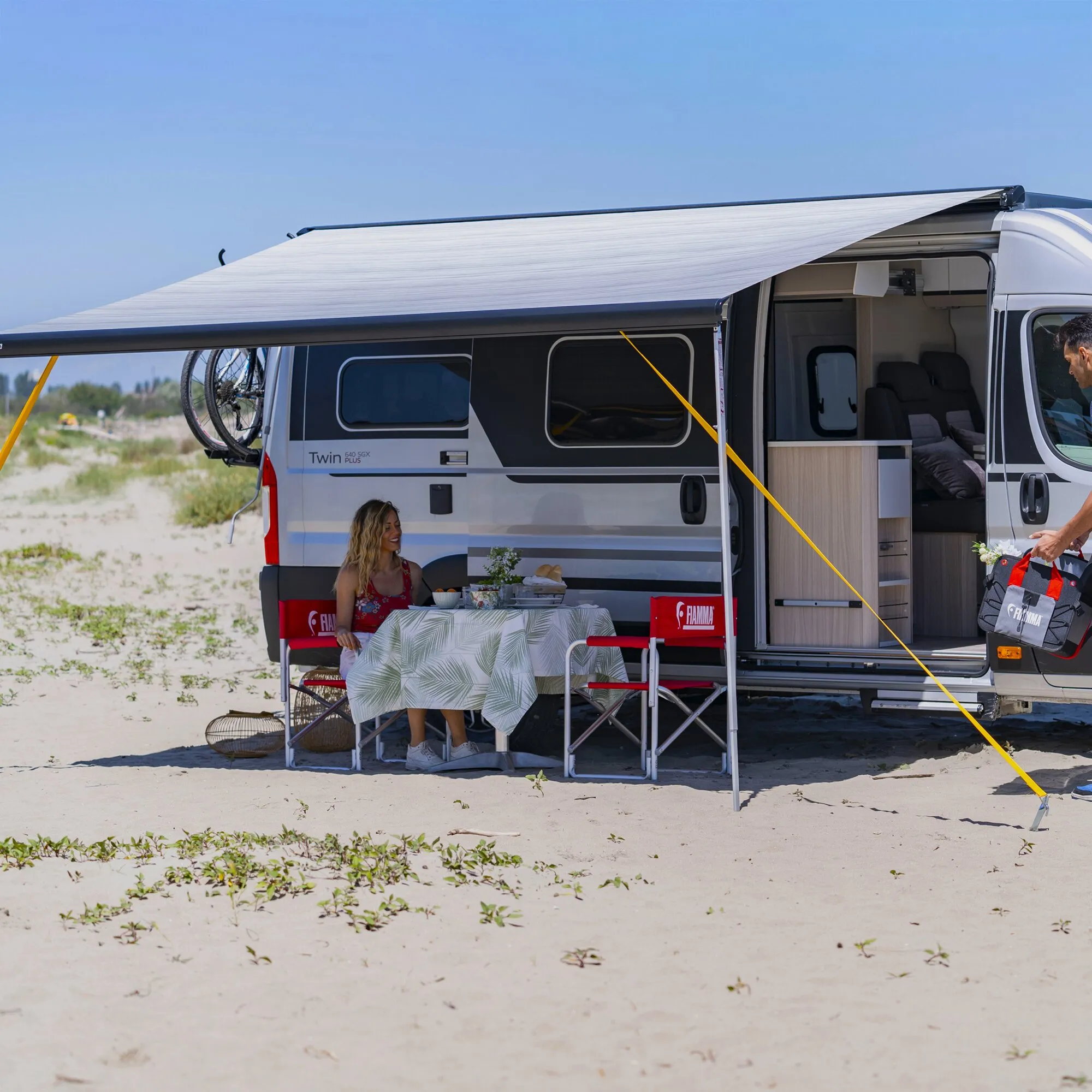 Gelbes Abspannband Tie Down S sichert die Markise eines Wohnmobils am Strand mit Hering im Sand