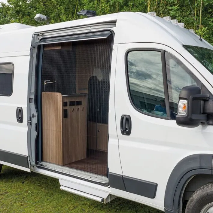 Weiße Fiat-Ducato-Campervan-Seitentür mit geschlossenem schwarzem Insektenschutzgitter REMIcare Van und sichtbarem Innenausbau