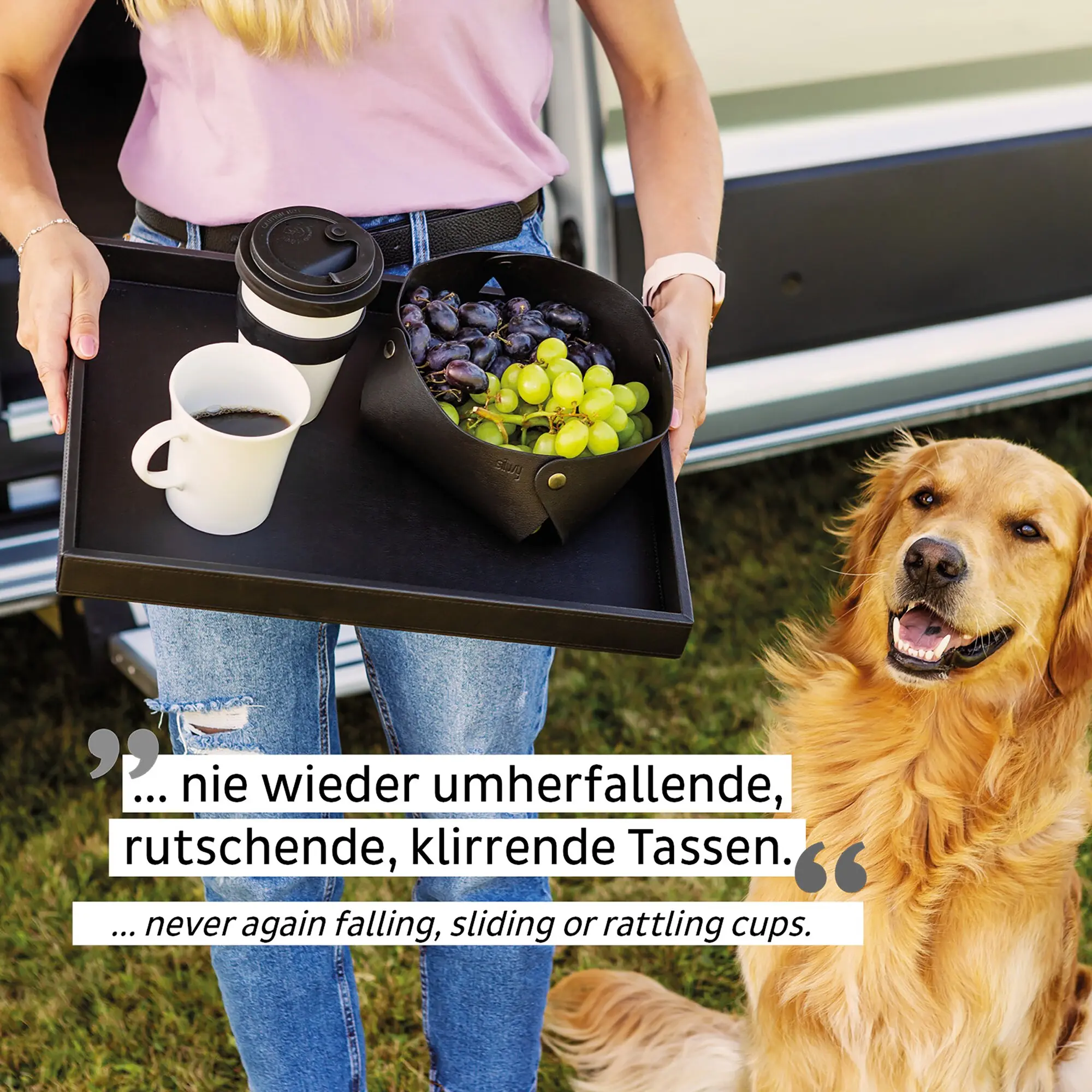 Person mit rosa Oberteil und Jeans hält eine schwarze Organizer-Tasche, sichtbar darin eine Magnet-Porzellantasse Camping, daneben Travel-Becher und weiße Kaffeetasse, Hund schaut zu