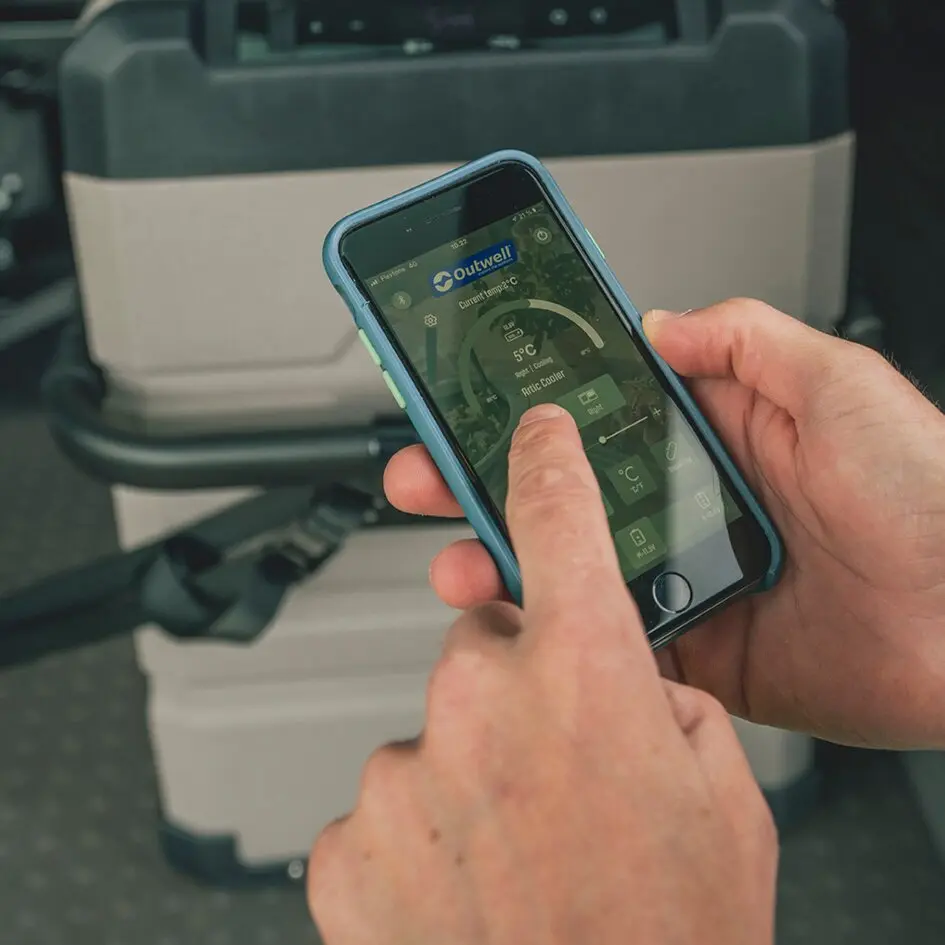 Hand hält Smartphone mit Outwell App; Display zeigt Temperatur- und Steuerungsdaten der Kühlbox, Hintergrund graue Arctic Frost Kühlbox 37 l