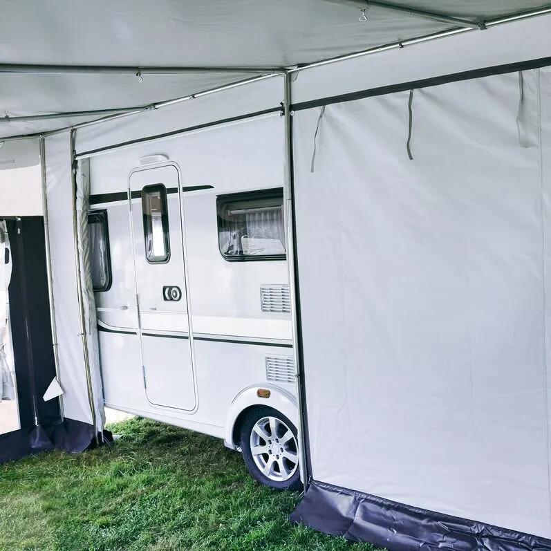 Weißes Dauervorzelt Allgäu 300 mit 650 cm Länge, aufgebaut vor einem weißen Wohnwagen auf einer Grasfläche