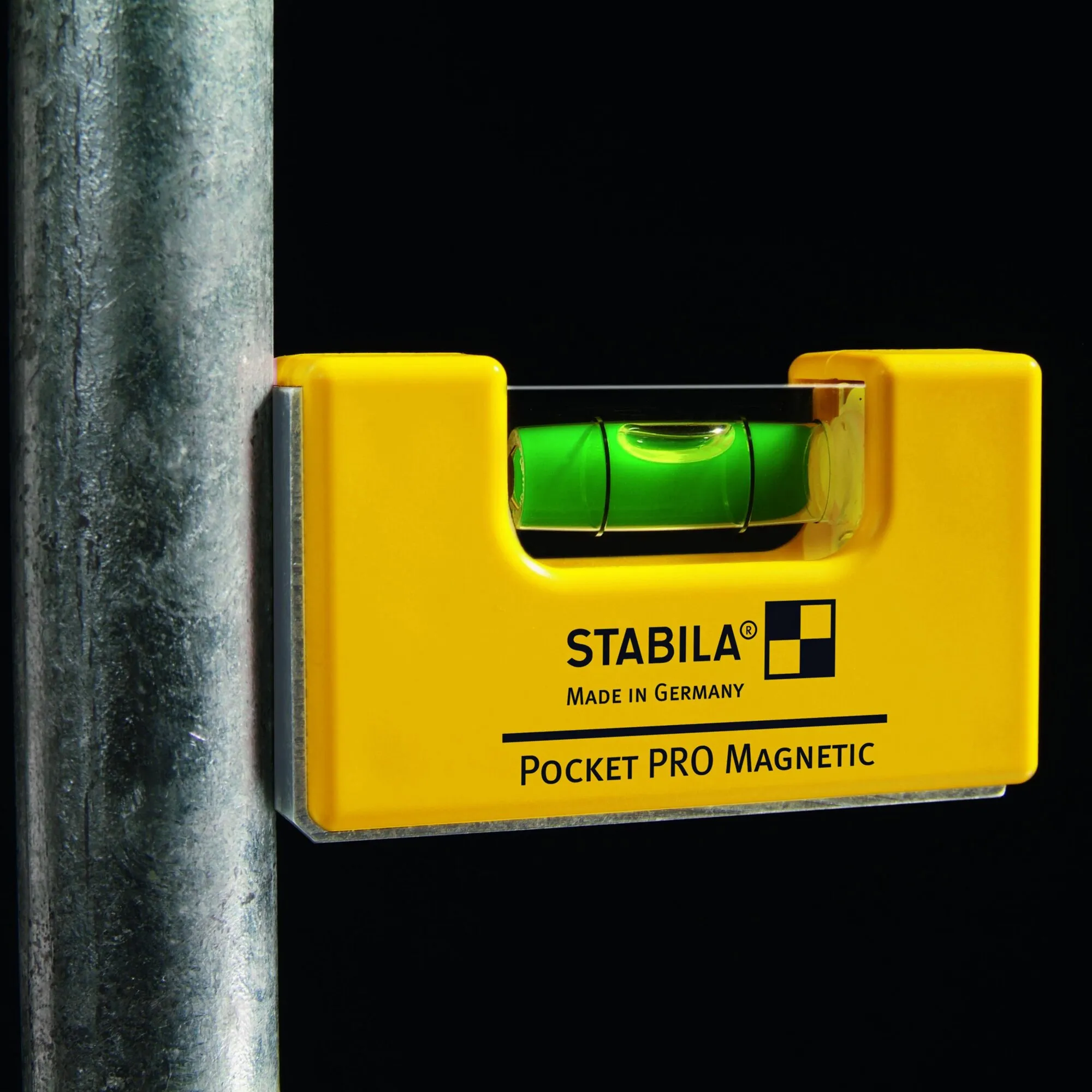 Gelbe magnetische STABILA Pocket Pro Wasserwaage mit grüner Libelle, an einem senkrechten Metallrohr befestigt