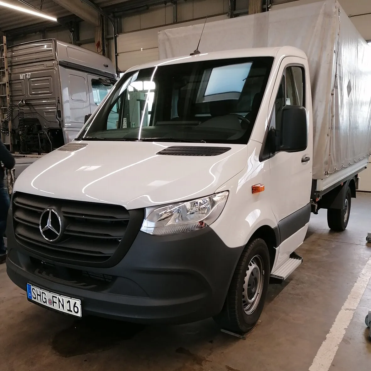Weißer Mercedes Sprinter mit sichtbarer Freistufe unter der Beifahrertür in einer Werkhalle, passend ab Baujahr 2006