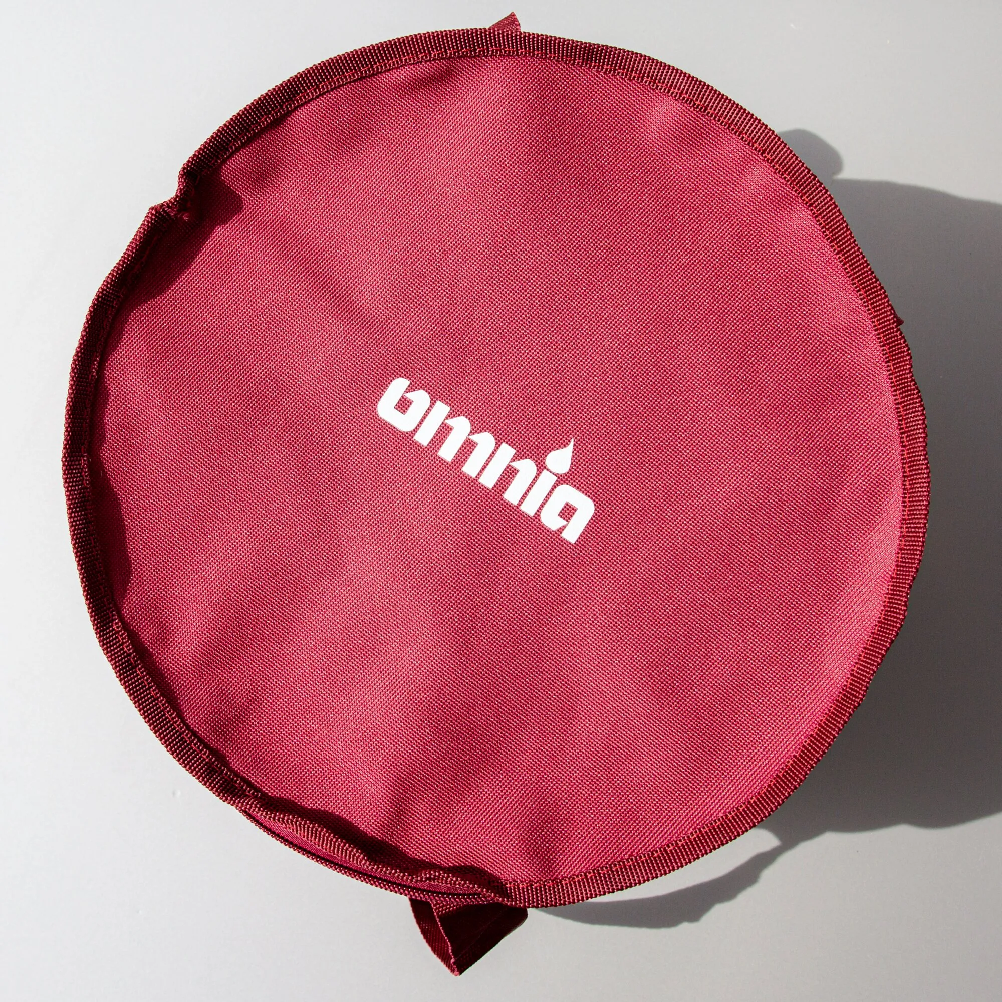 Rote runde Aufbewahrungstasche aus textilem Gewebe mit weißem Umami-Logo und angenähten Laschen, 17 x 29 cm