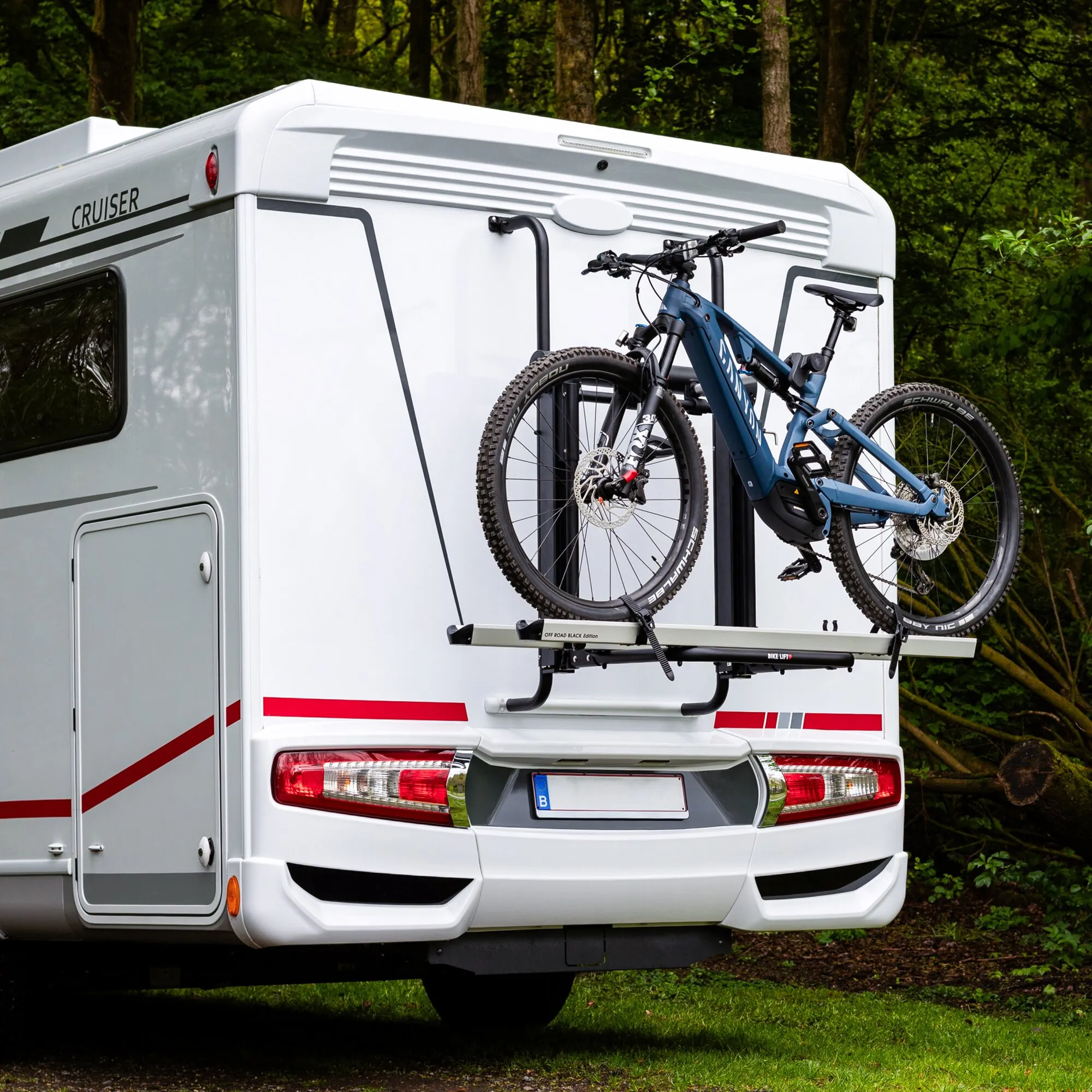 Heckträger Bike Lift Offroad Black an der Rückseite eines weißen Wohnmobils; zwei blaue Mountainbikes mit Scheibenbremsen am Träger