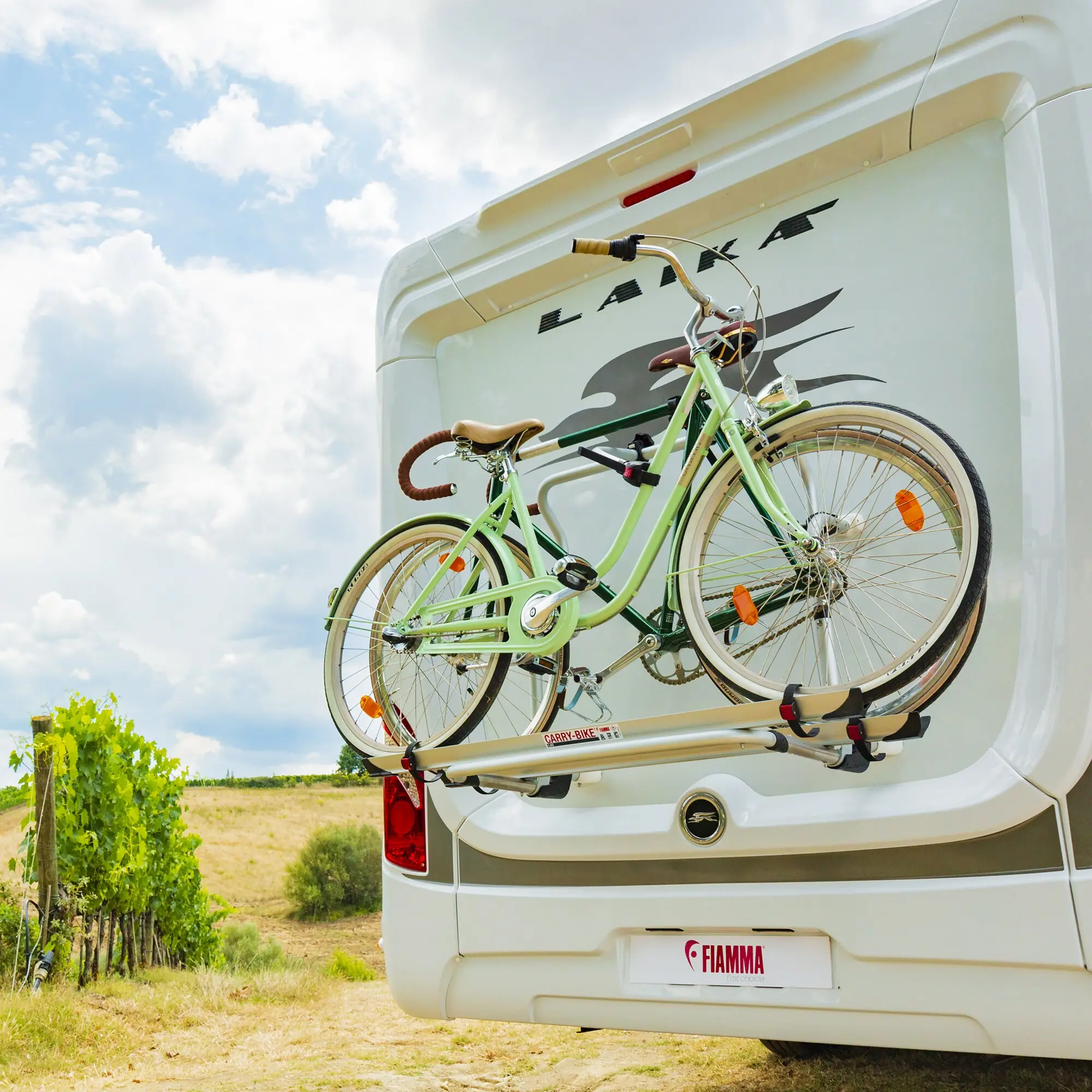 Rückseite eines weißen Wohnmobils mit Carry-Bike Pro C L80 Fahrradträger, zwei grün lackierte Fahrräder montiert, rote Rückleuchte unten