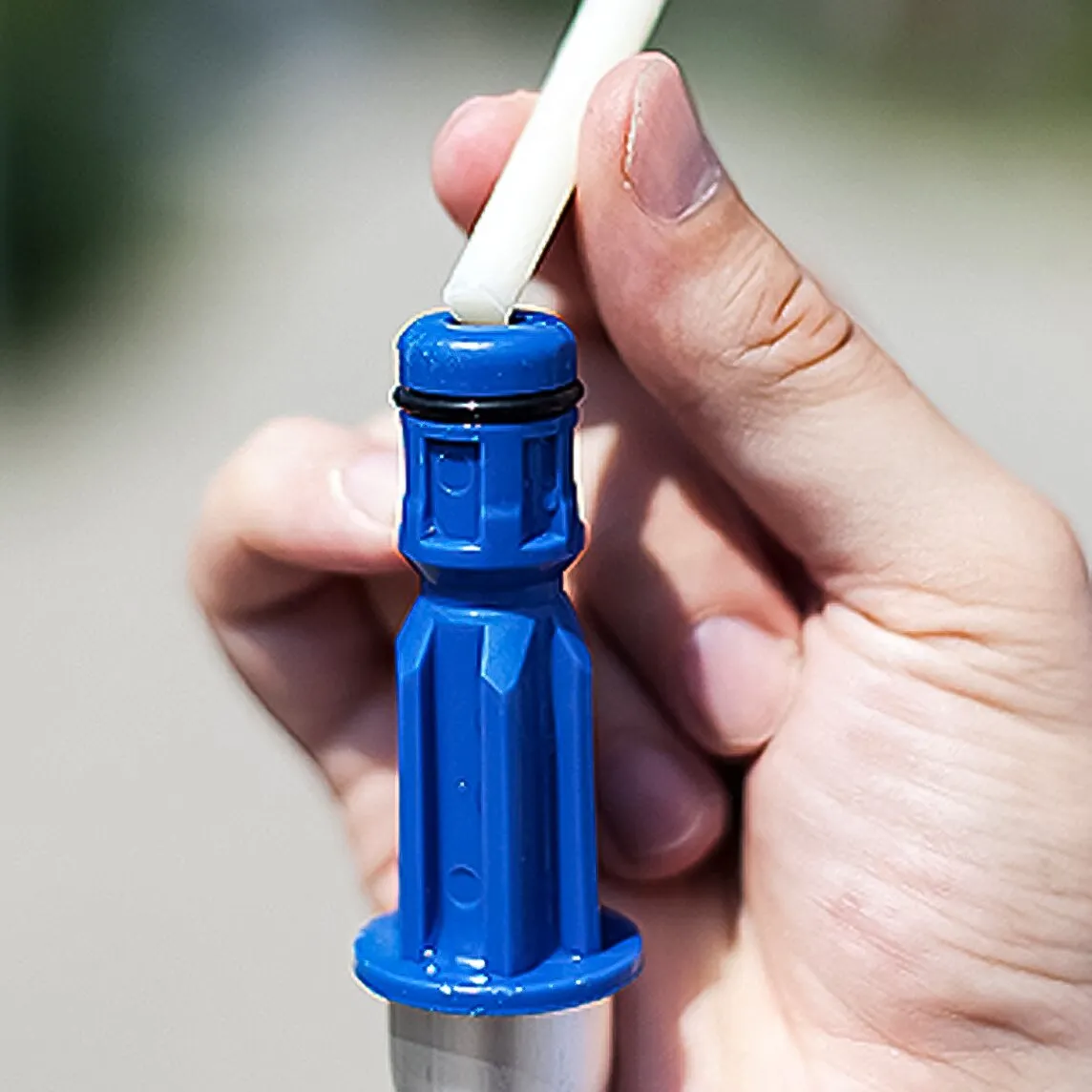 Detailaufnahme einer blauen Wasserdurchlaufstange mit weißem Stab, die von einer Hand gehalten wird