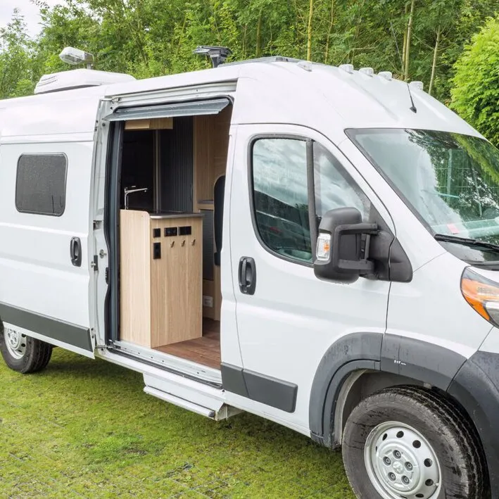 Weiße Insektenschutztür REMIcare Van an der geöffneten Seitentür eines Fiat Ducato Wohnmobils im Außenbereich